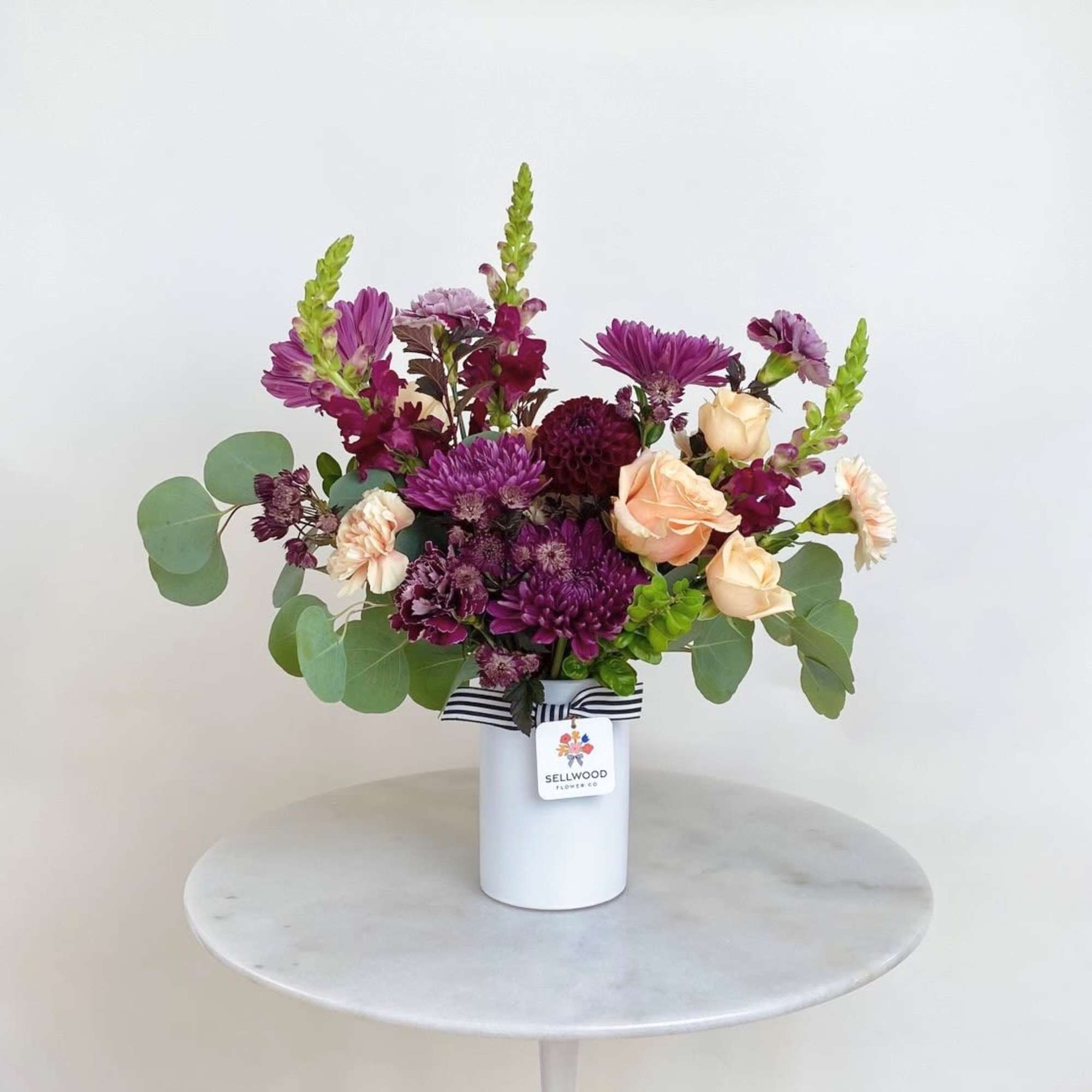 Purple and peach mixed bouquet in a white vase