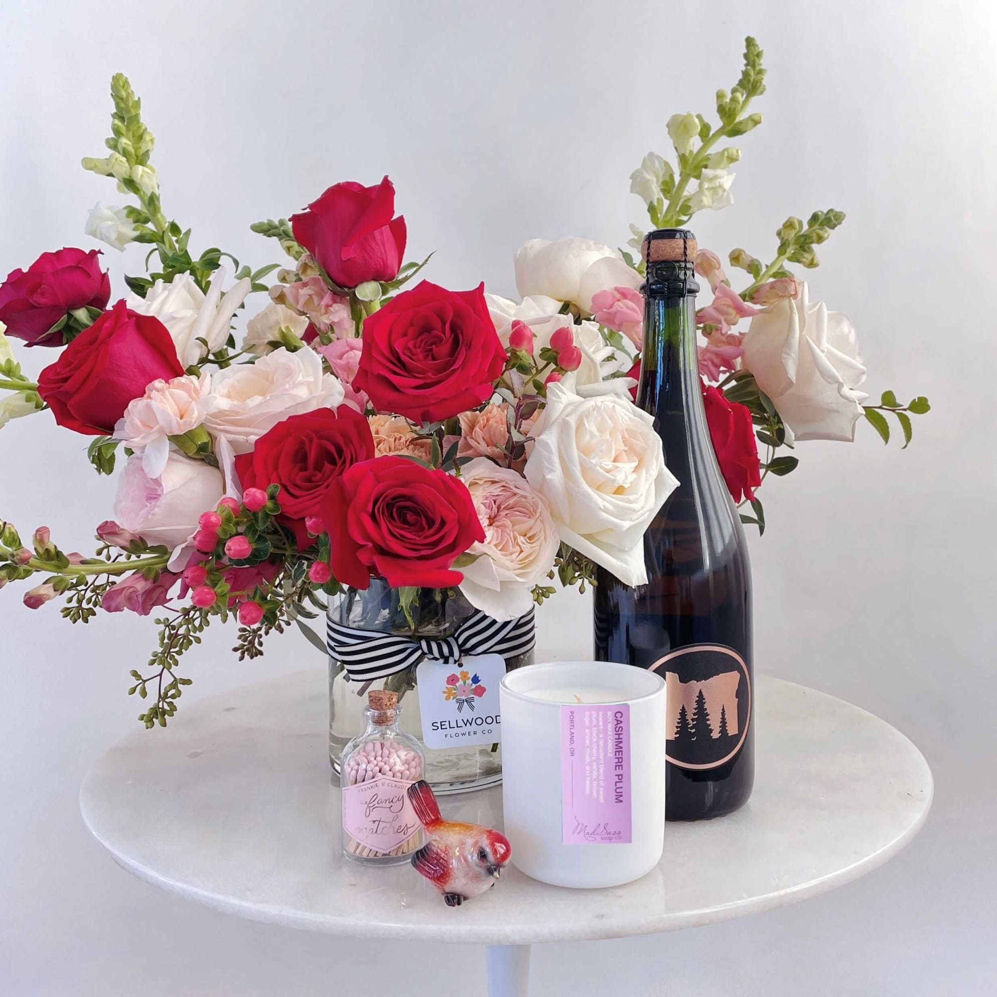 Bouquet of red and white roses in a glass vase with a champagne bottle and candle