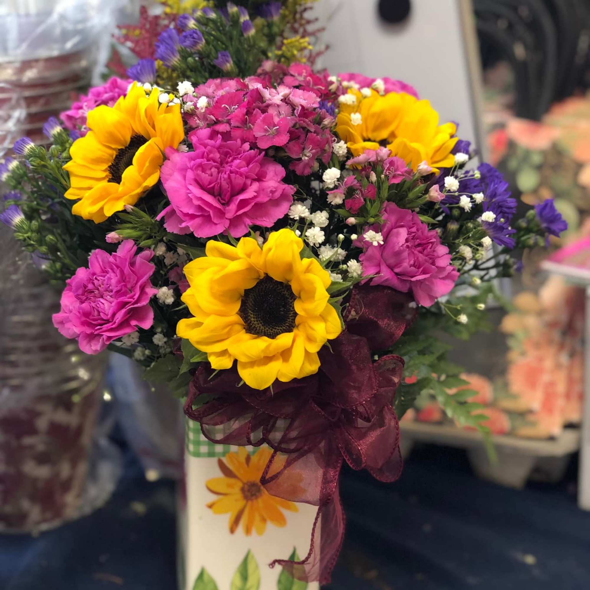 Bouquet of sunflowers and pink carnations in a decorative vase