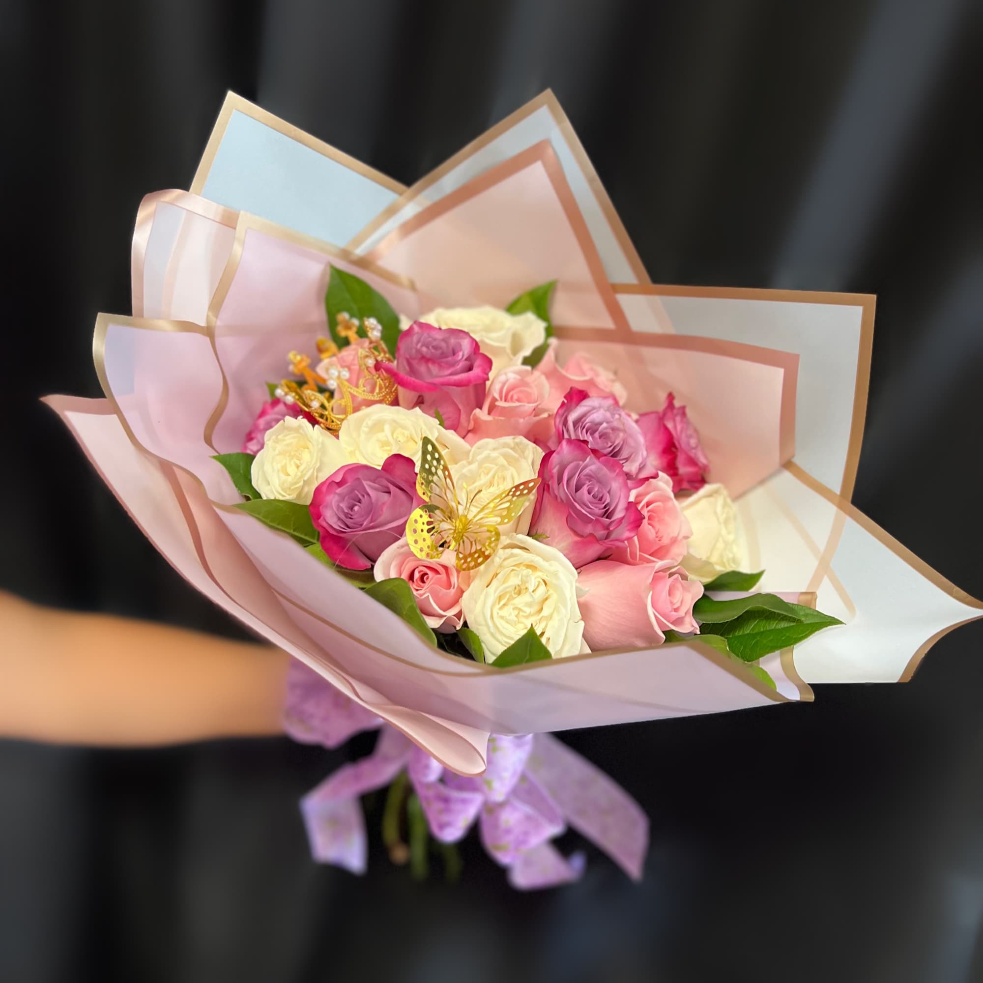 Bouquet of pink, purple, and white roses wrapped in pastel paper