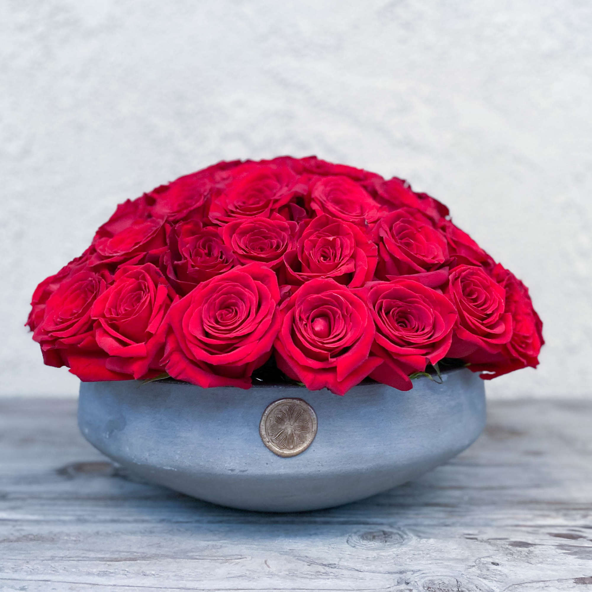 Red roses arranged in a low gray bowl