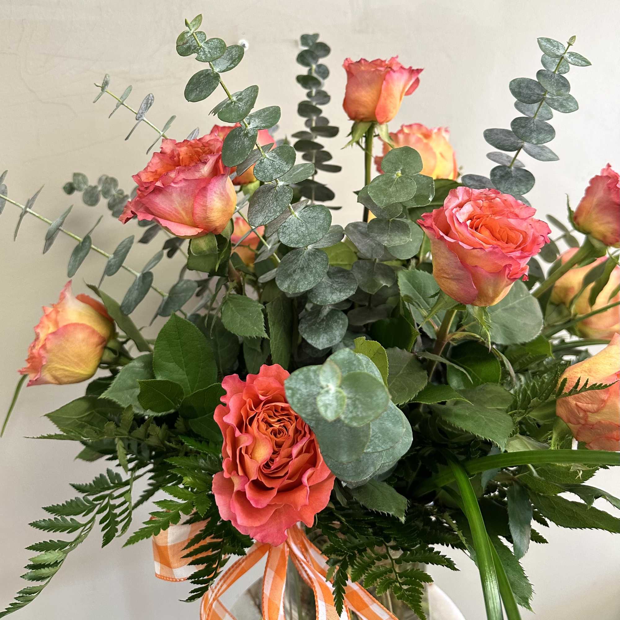 Bouquet of coral-orange roses with eucalyptus in a vase