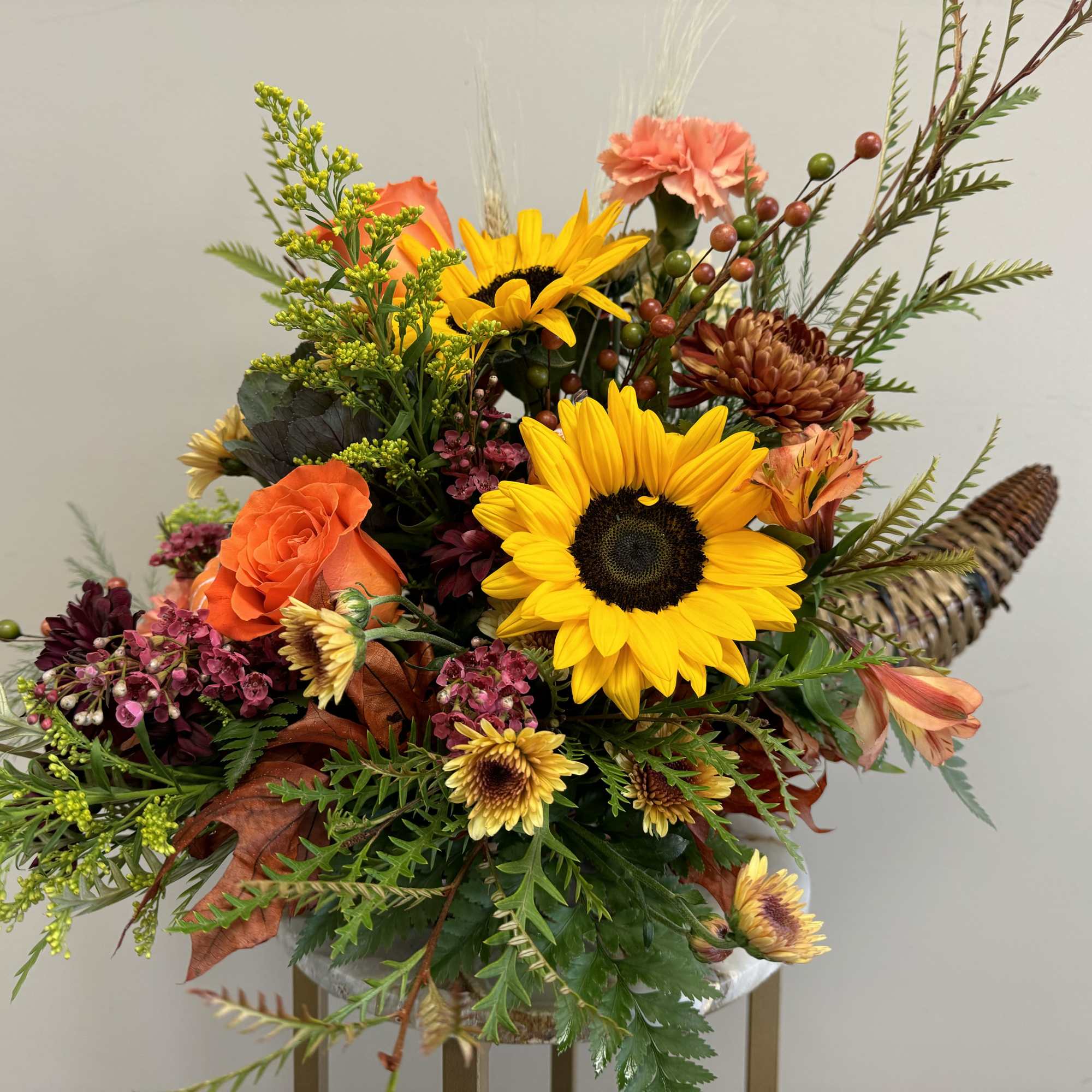 Bouquet with sunflowers, orange roses, and mixed fall flowers in a vase