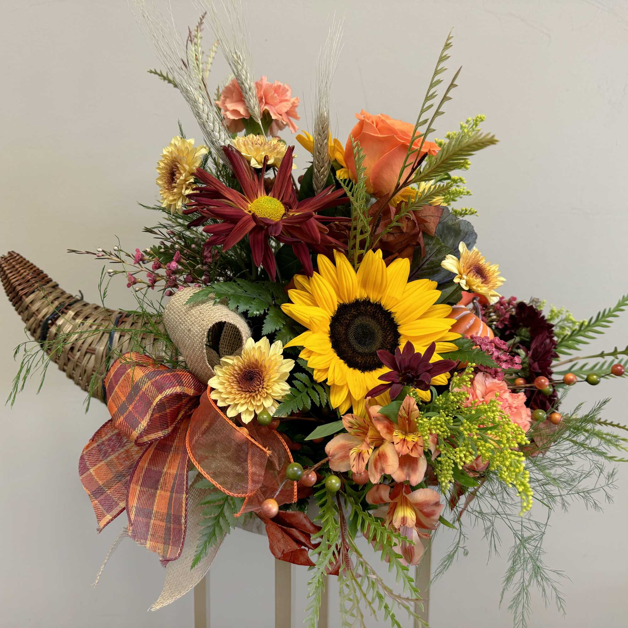 Autumn bouquet with sunflowers, roses, and mixed blooms in a woven cornucopia container