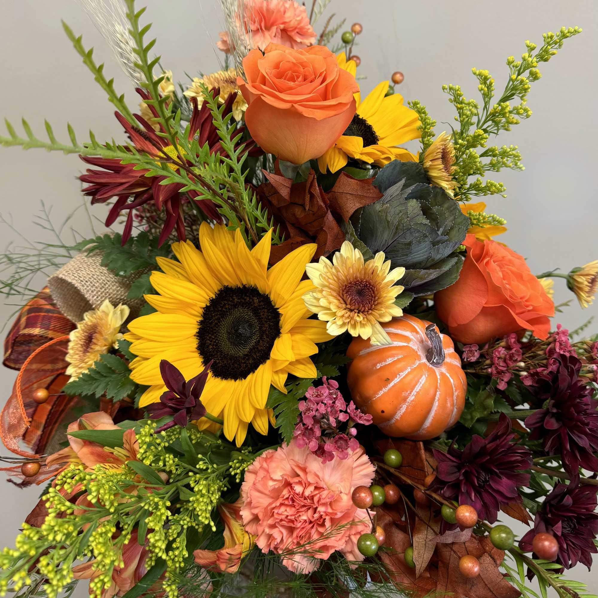 Autumn bouquet with sunflowers, orange roses, carnations, and a small pumpkin