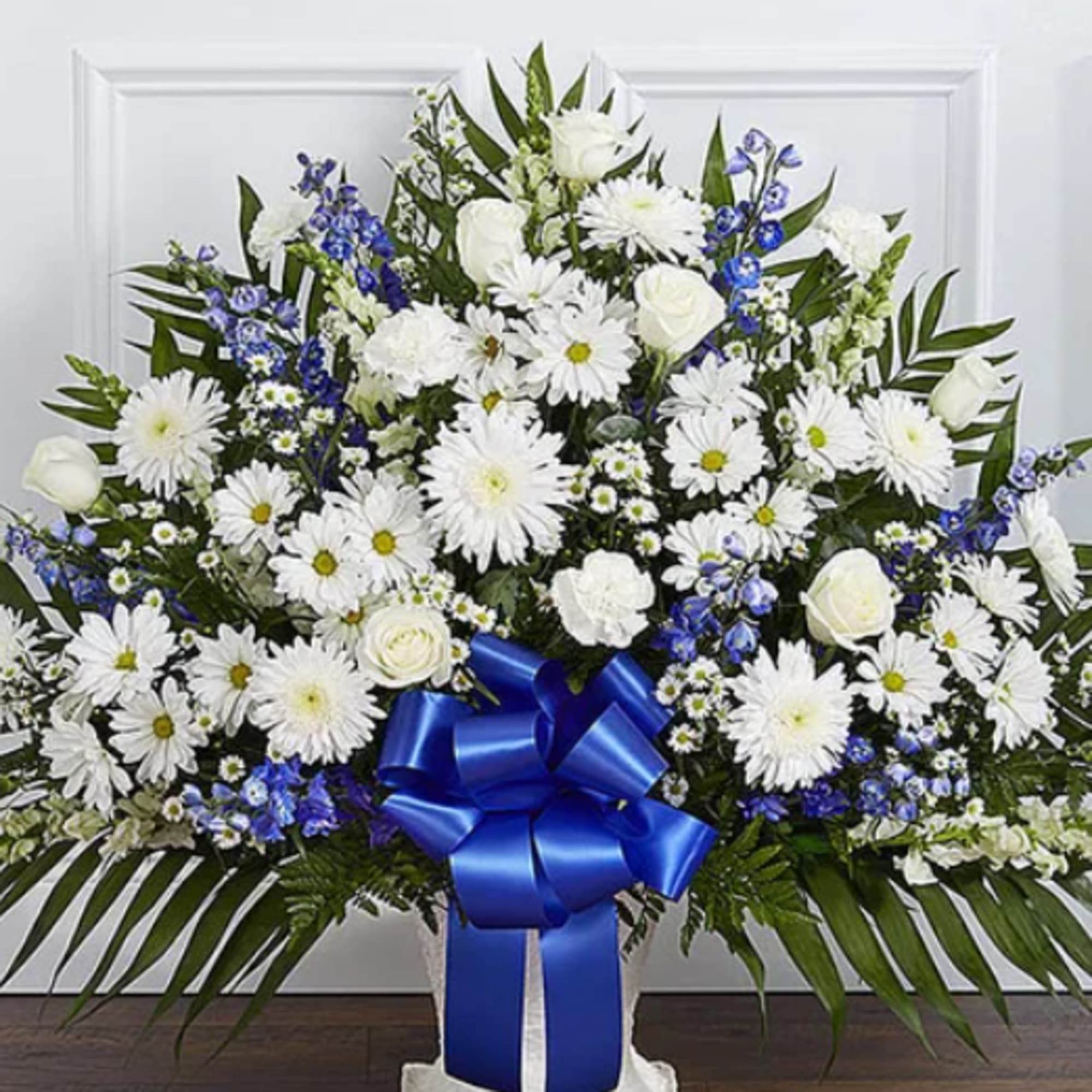 White floral standing spray with blue ribbon and daisies