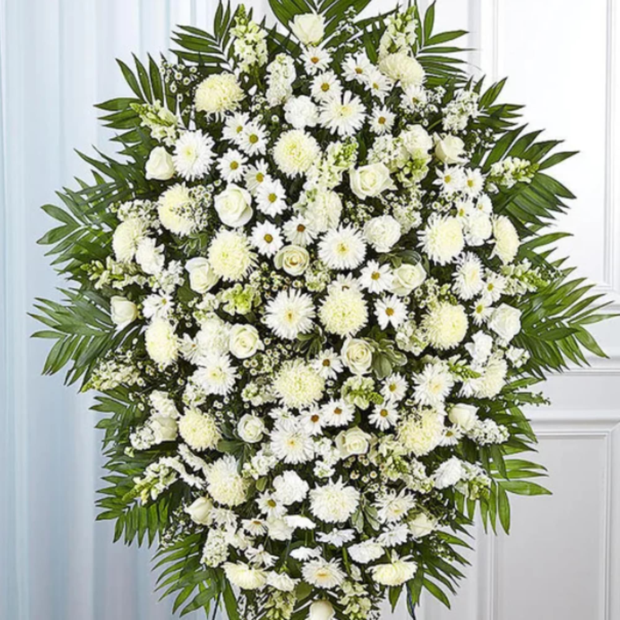 Large white funeral spray with daisies, roses, and palm fronds