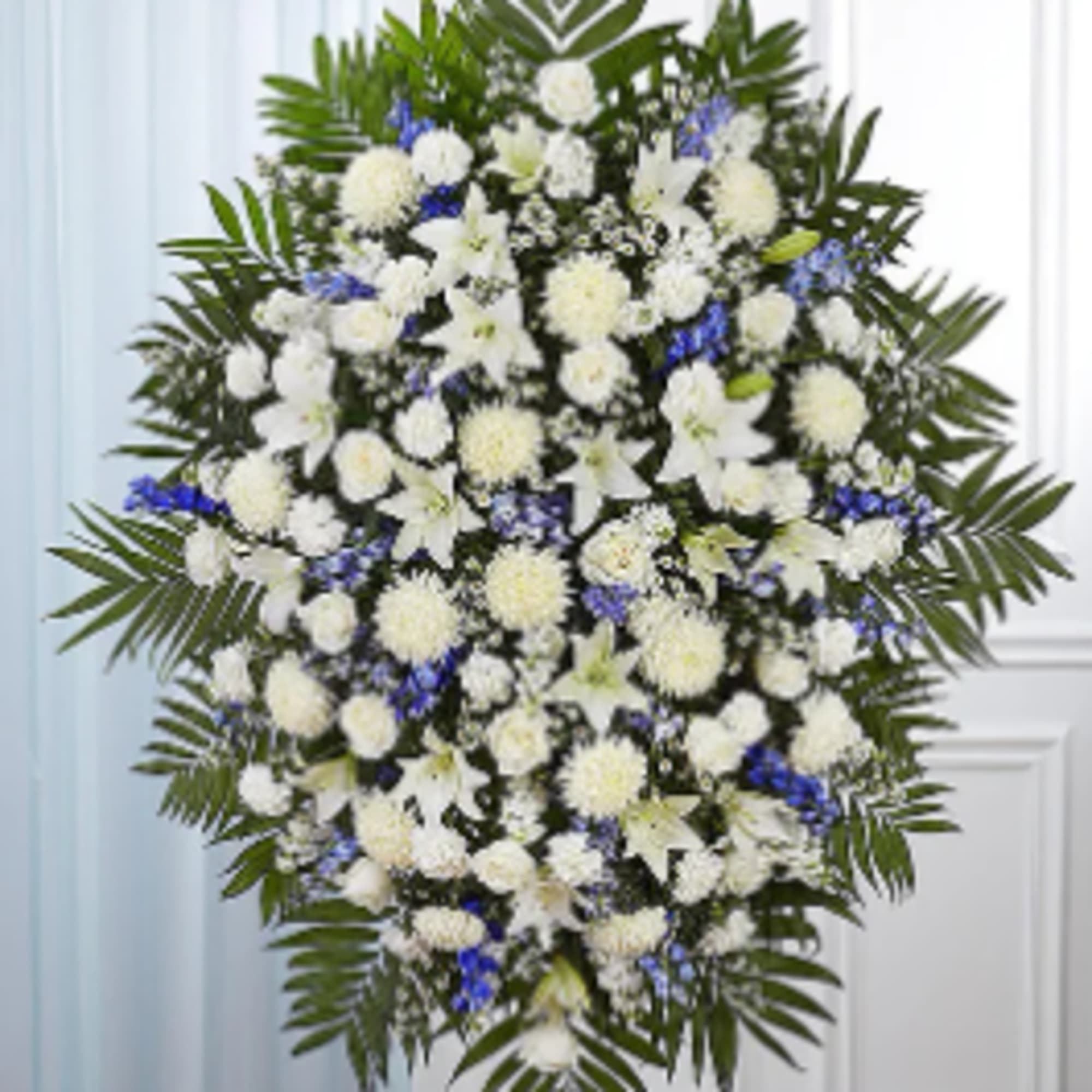 White funeral spray with blue accents and palm fronds