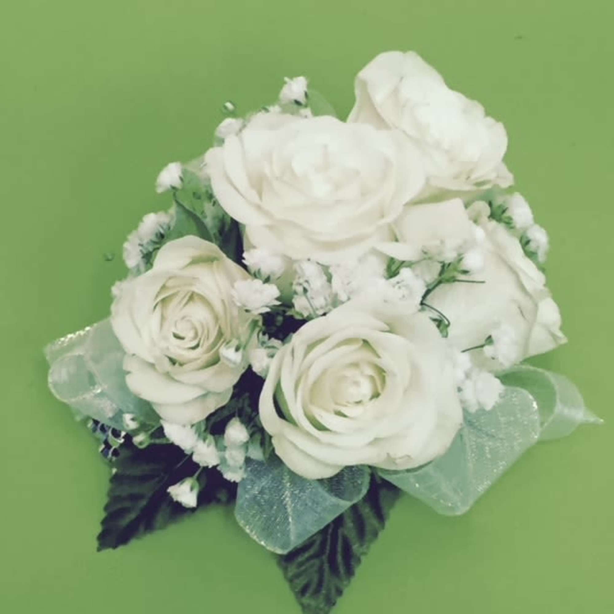 White rose bouquet with small white filler flowers and a pale ribbon