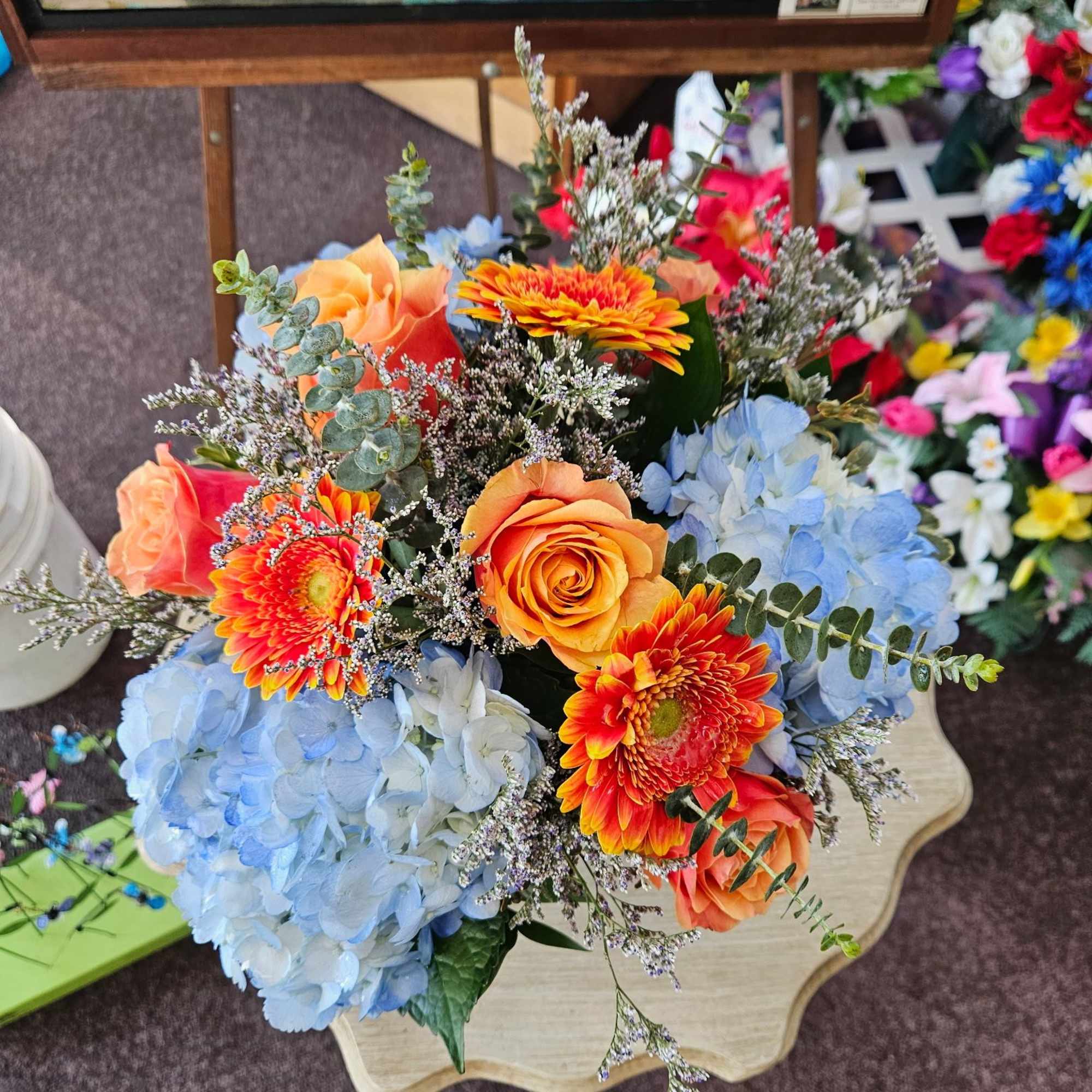 Lovely mix of blue hydrangea, cherry brandy roses and gerbera arranged in