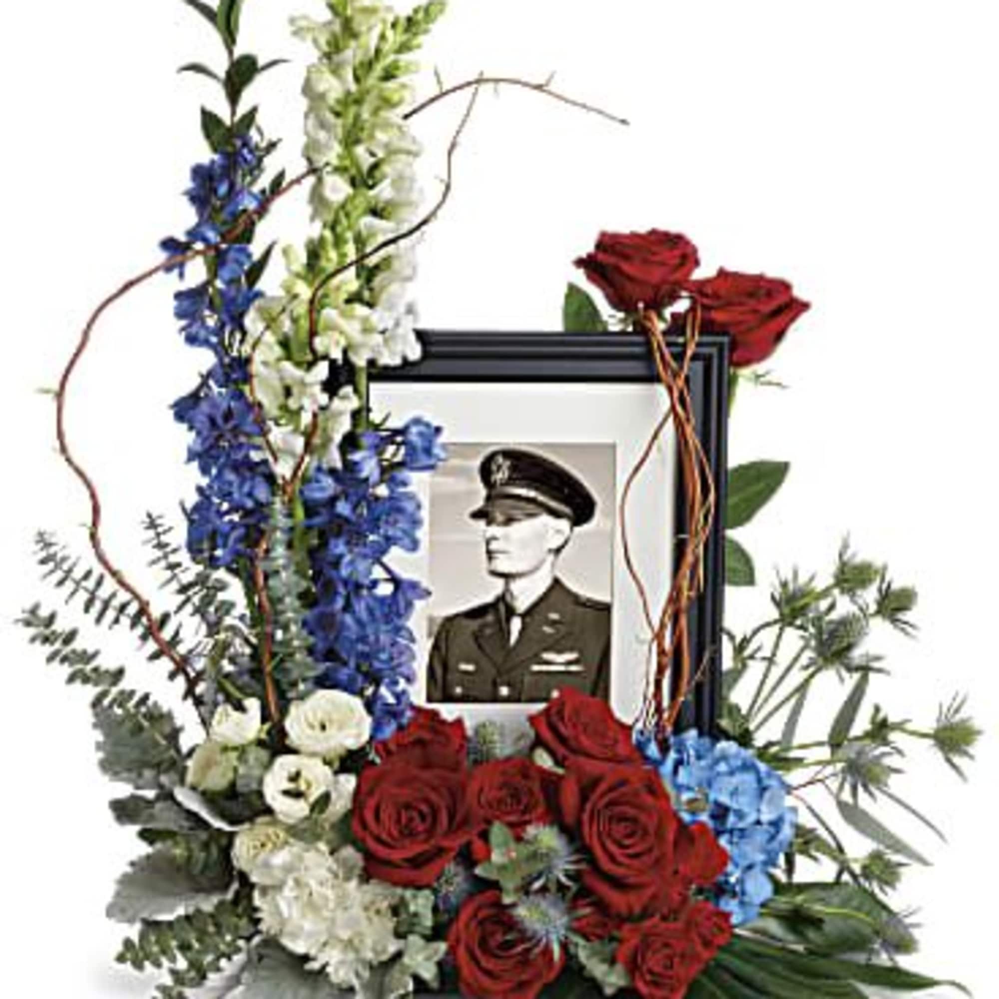 Memorial floral frame with red roses, blue and white flowers, and a portrait photo