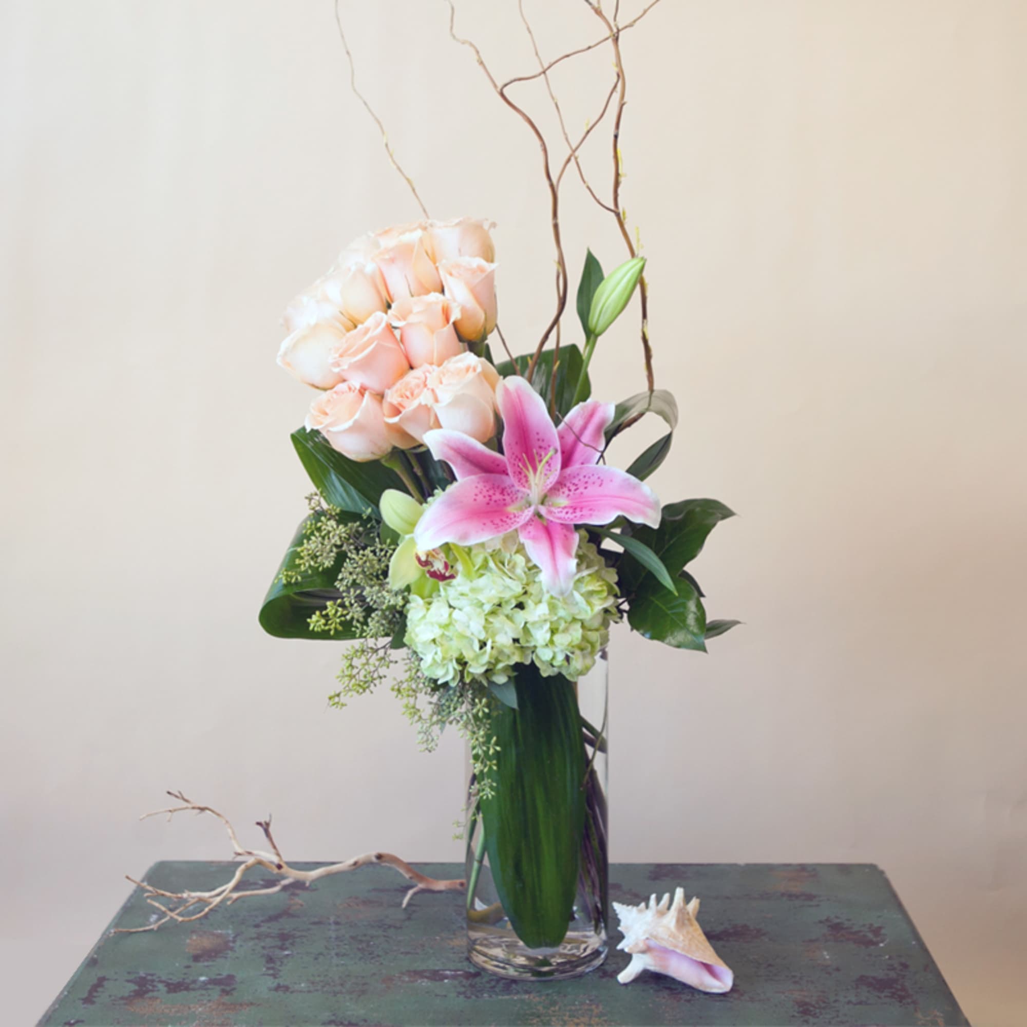 Pink lilies and pale roses arranged in a clear glass vase