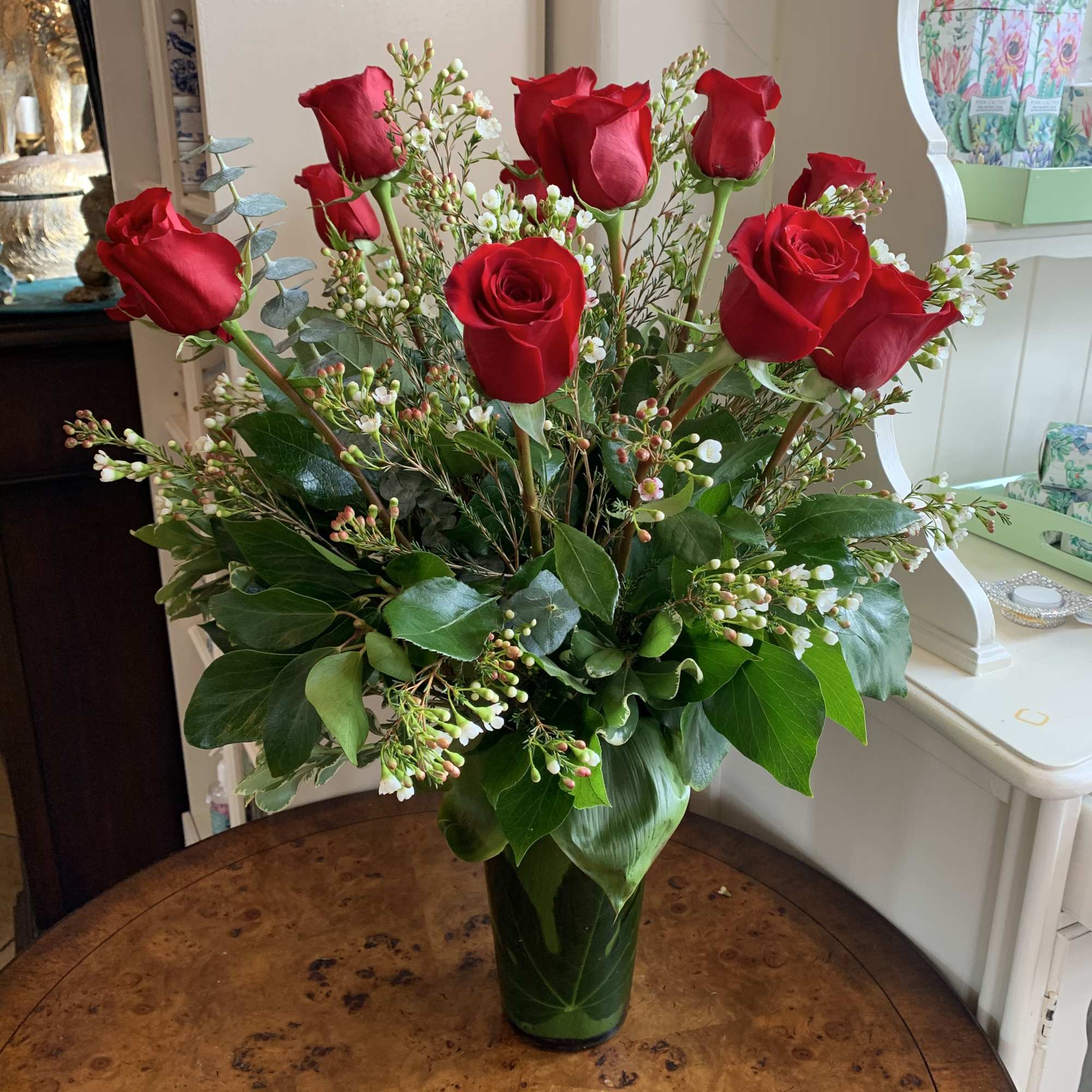 Red roses arranged in a clear glass vase with white filler flowers