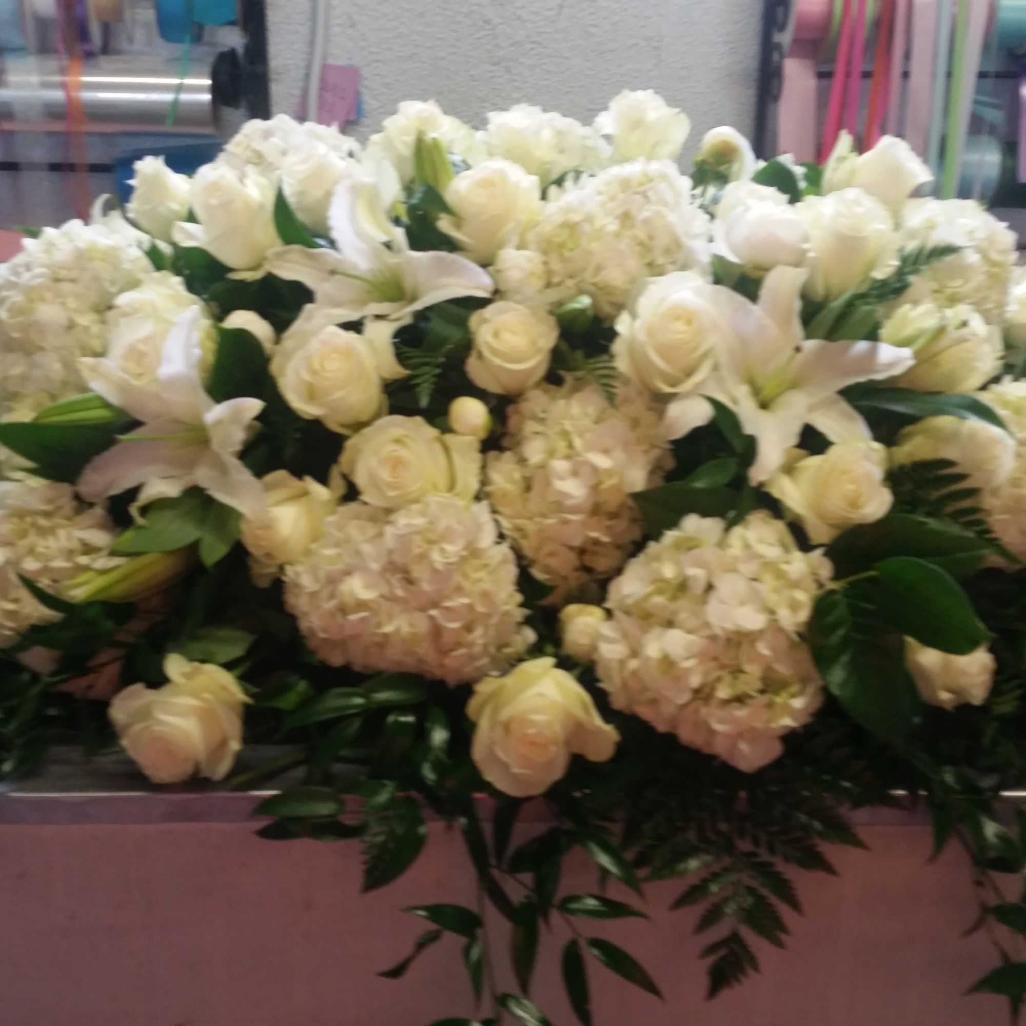 Large white floral arrangement with roses, lilies, and hydrangeas