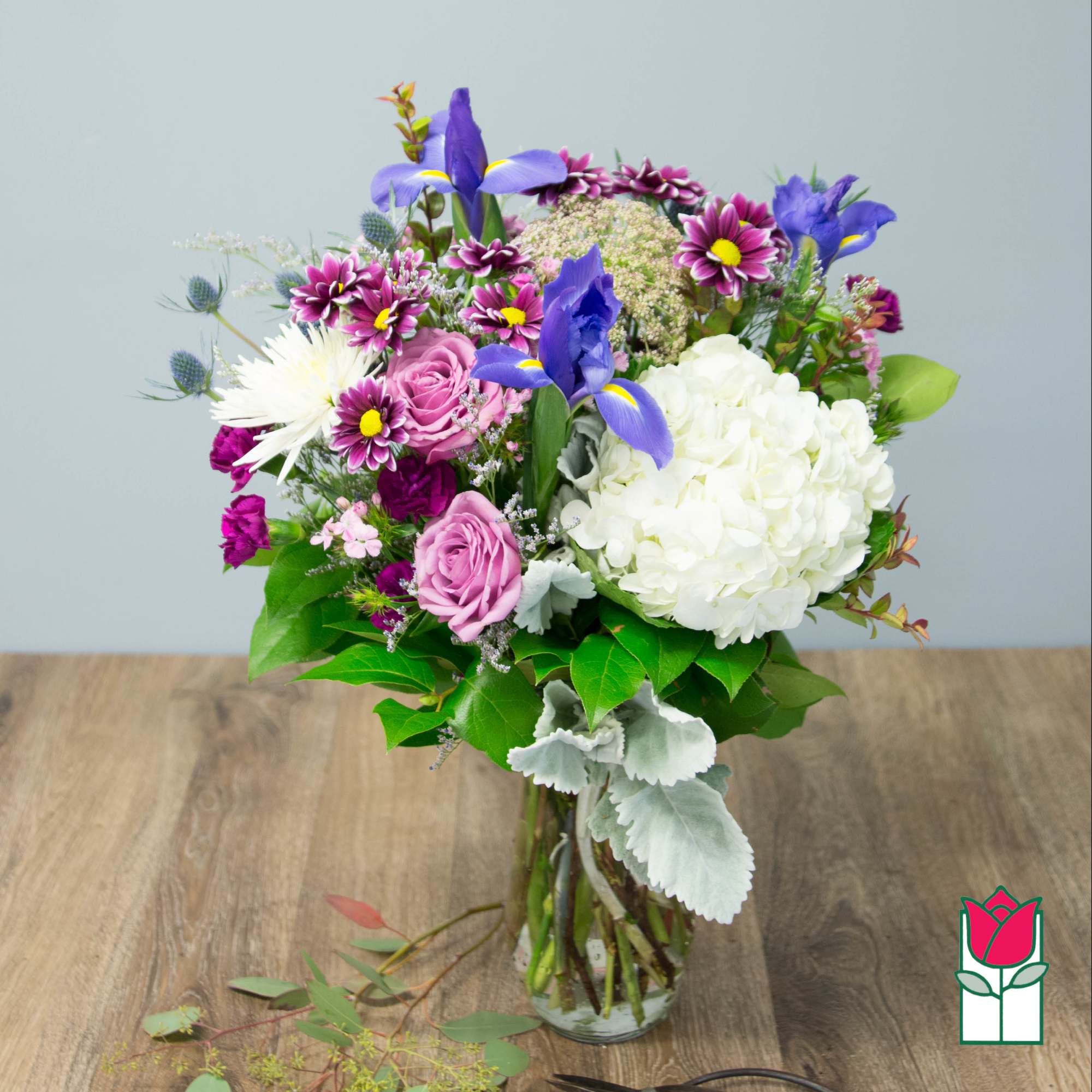 Mixed bouquet with purple irises, pink roses, and white hydrangea in a glass vase