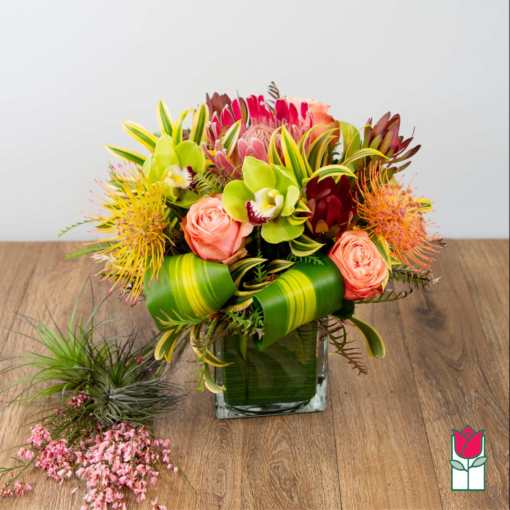 Tropical bouquet with pink roses and green orchids in a glass vase