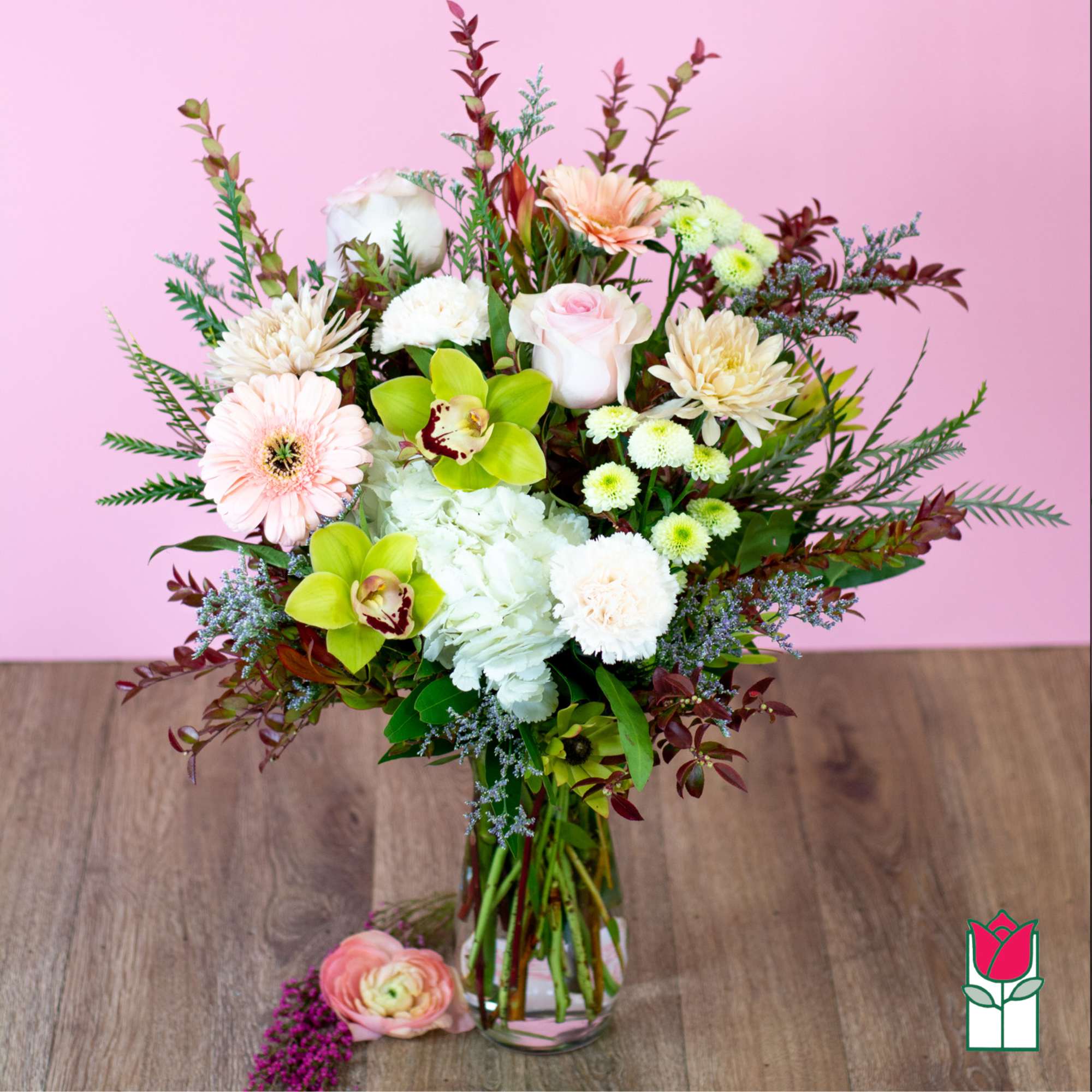 Mixed bouquet in a clear glass vase with pink, white, and green flowers