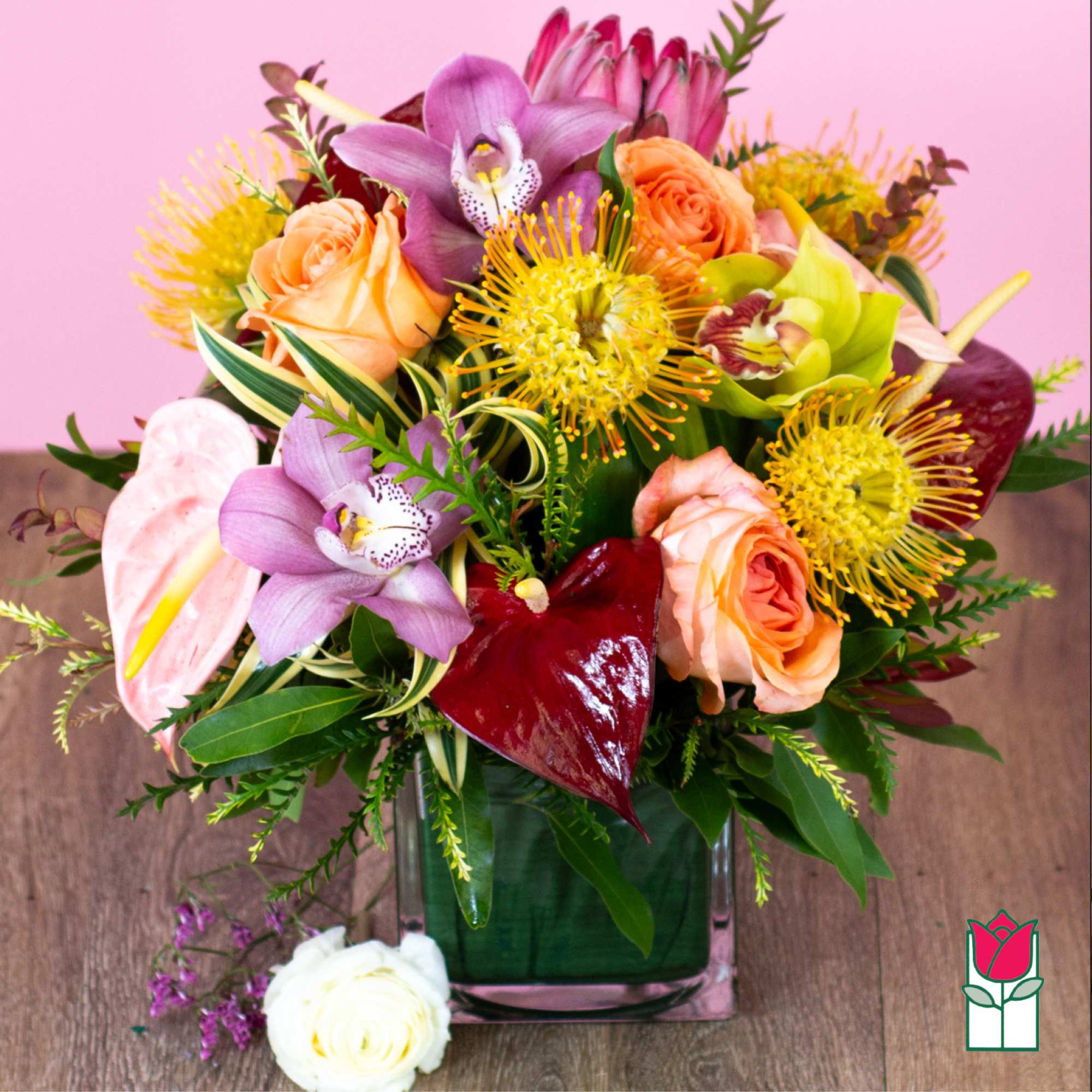 Mixed bouquet of orchids, roses, and tropical blooms in a glass vase