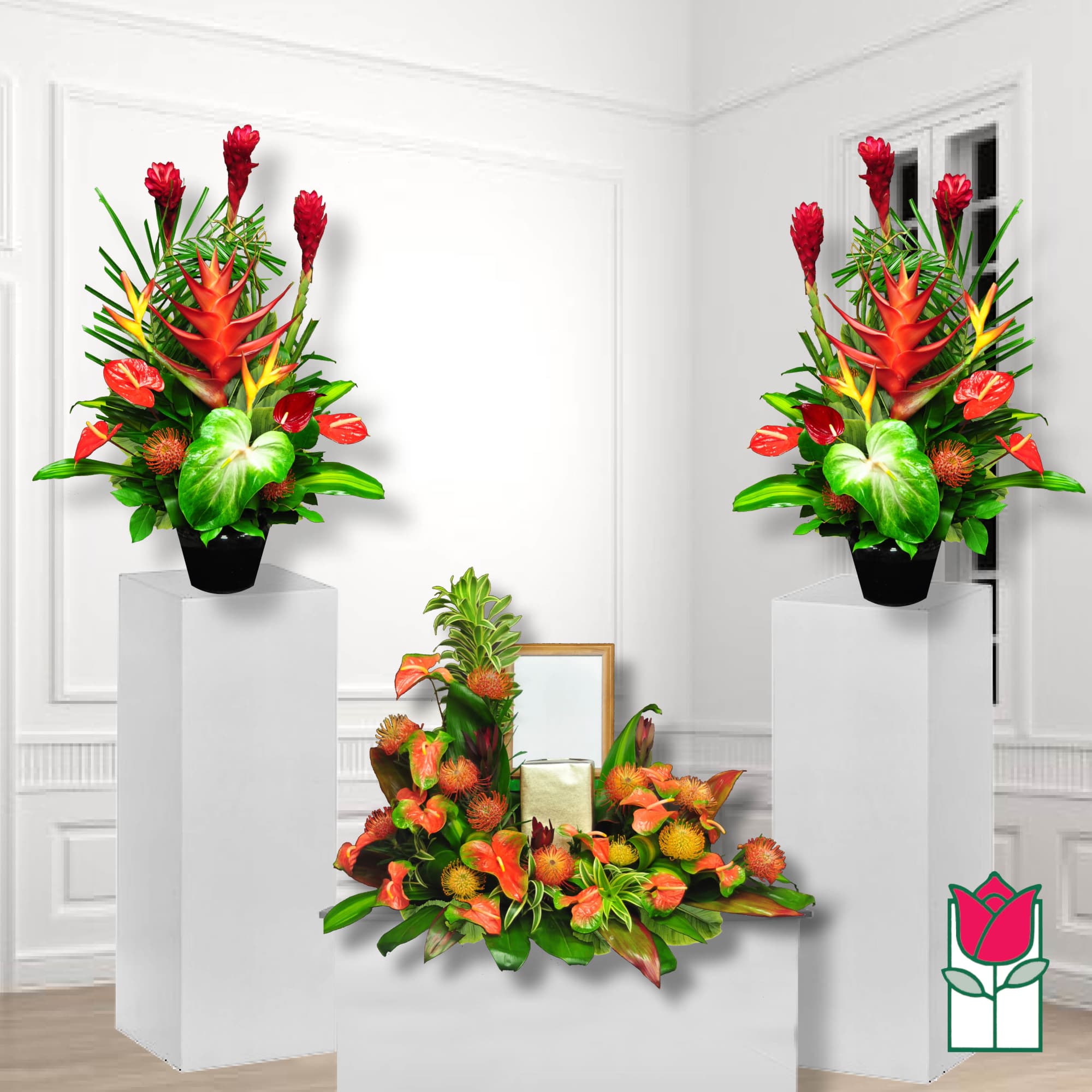 Tropical floral arrangement with red and orange blooms in black pots