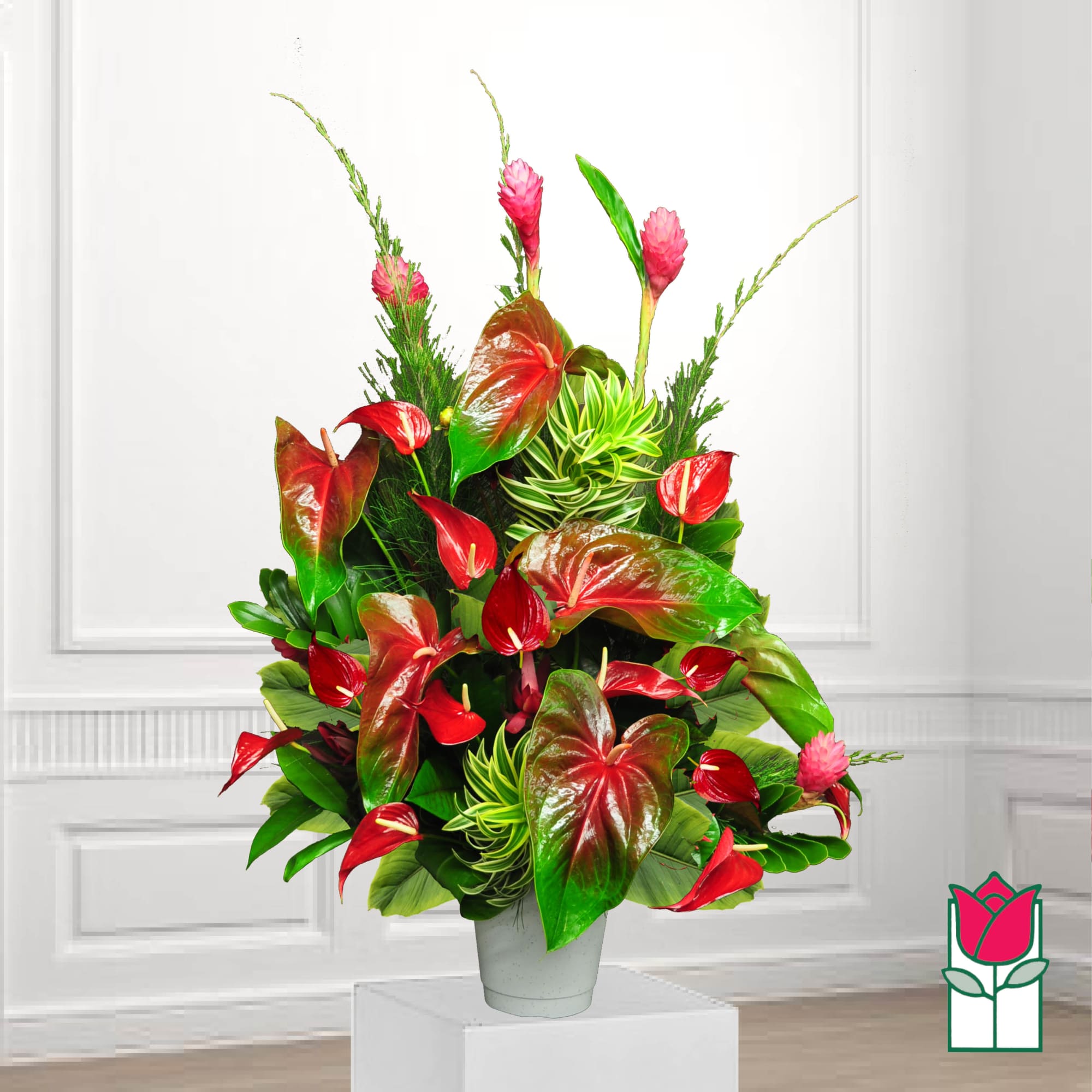 Tropical arrangement with red anthuriums and pink ginger in a white vase