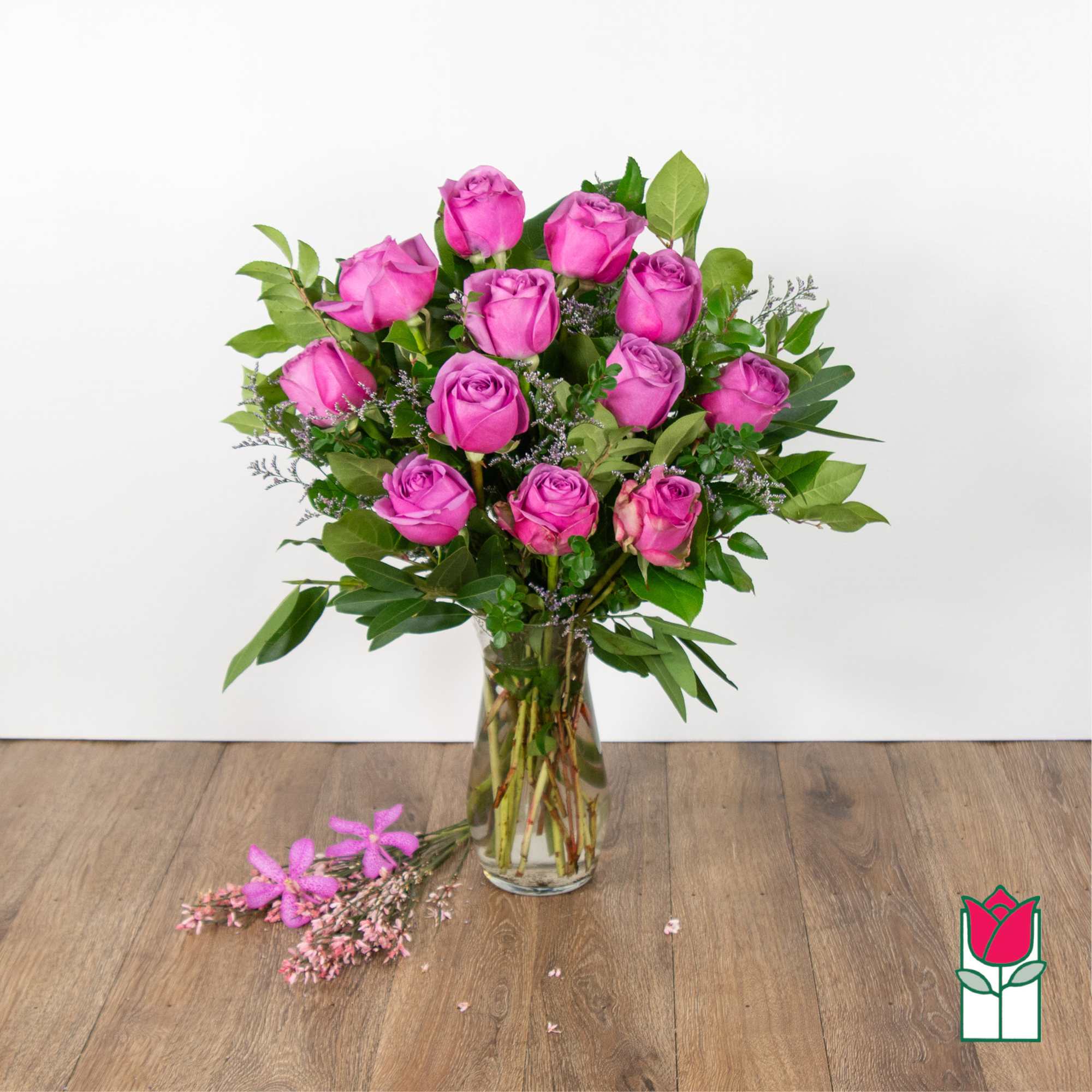 Pink roses arranged in a clear glass vase with greenery