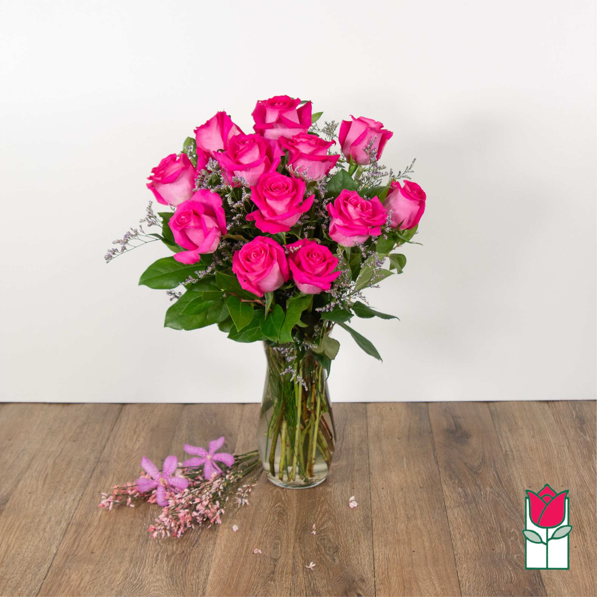 Pink roses arranged in a clear glass vase with greenery
