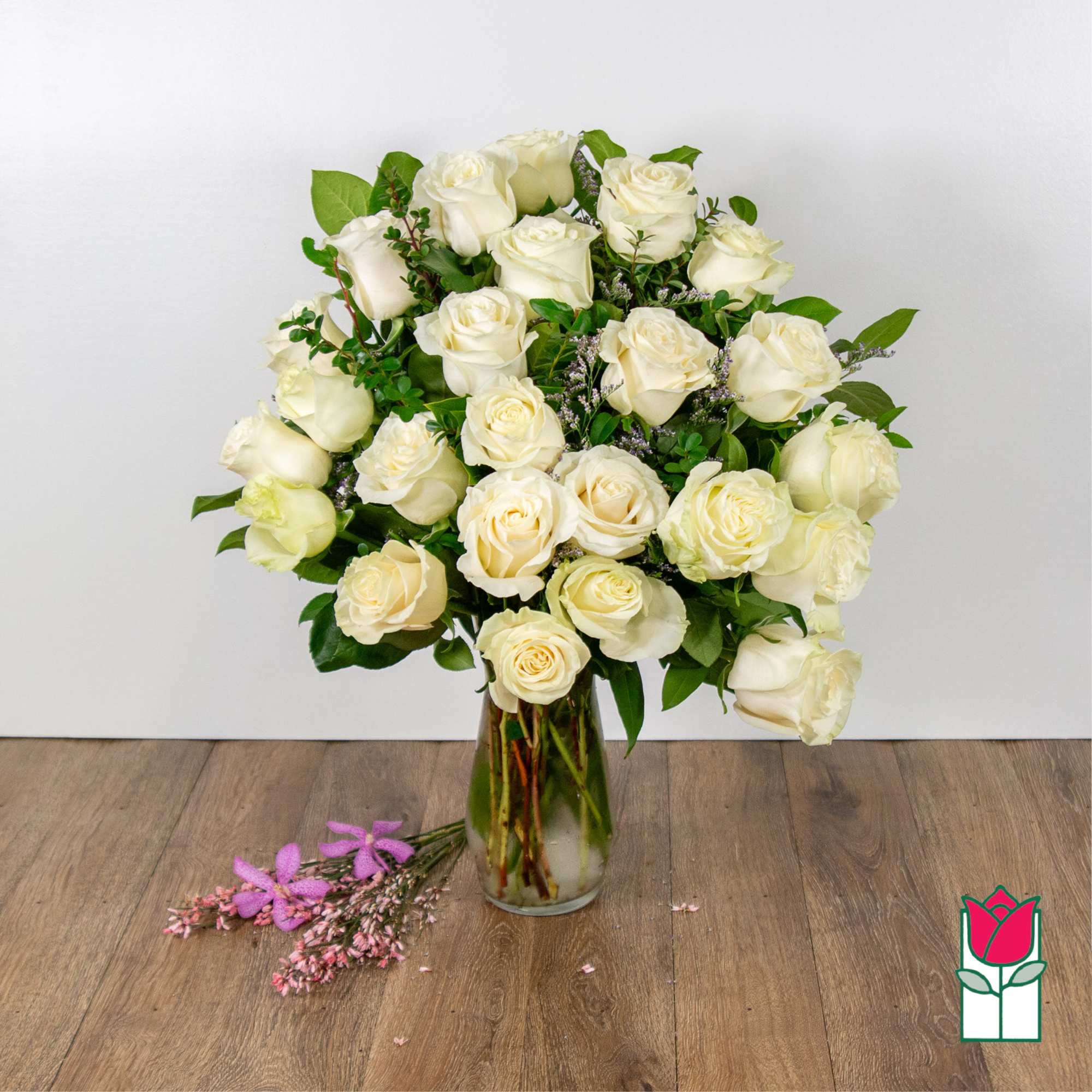 Bouquet of white roses in a clear glass vase with greenery.