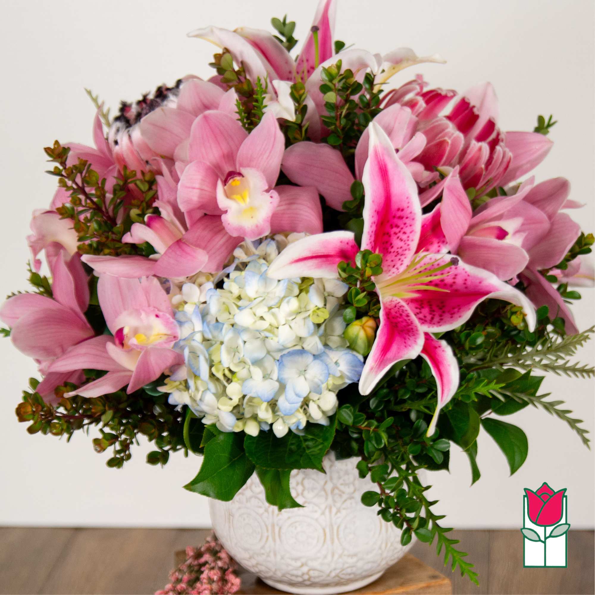 Pink lilies and hydrangeas arranged in a white vase