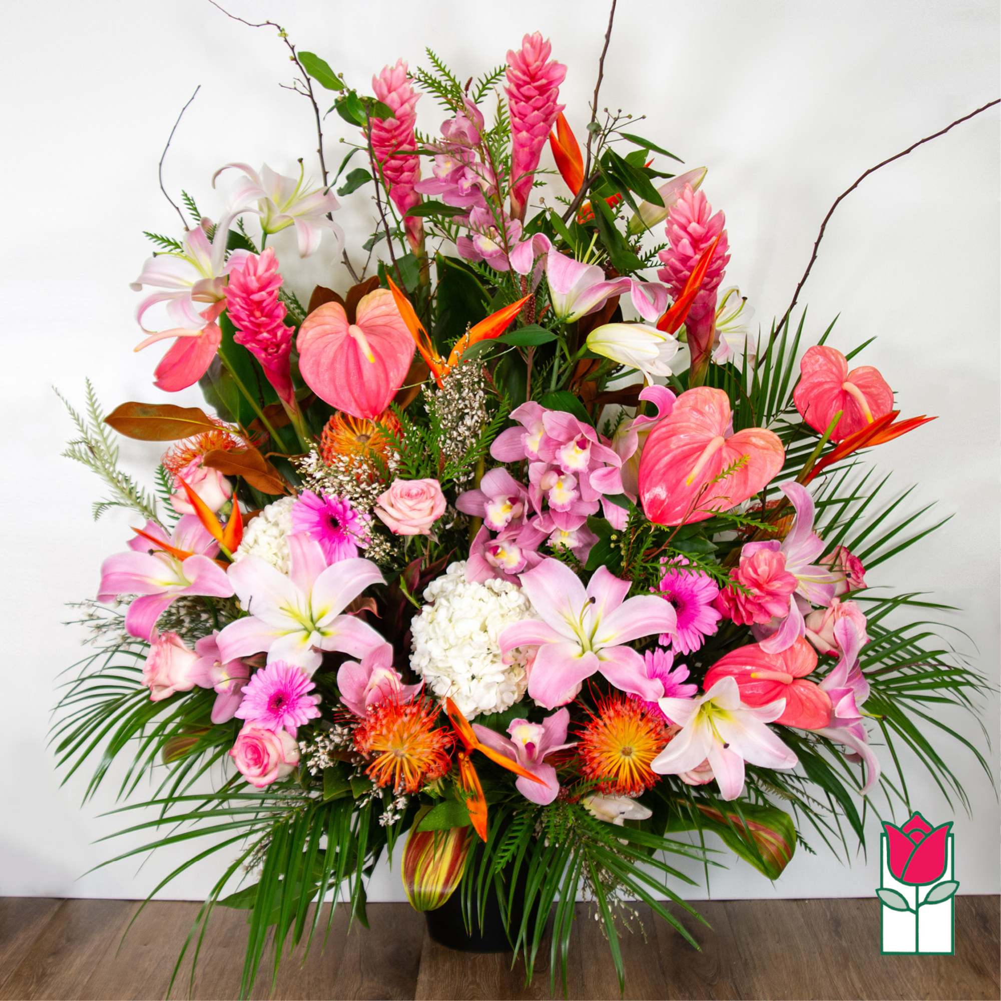 Large tropical bouquet with pink lilies, orchids, and anthuriums in a black vase