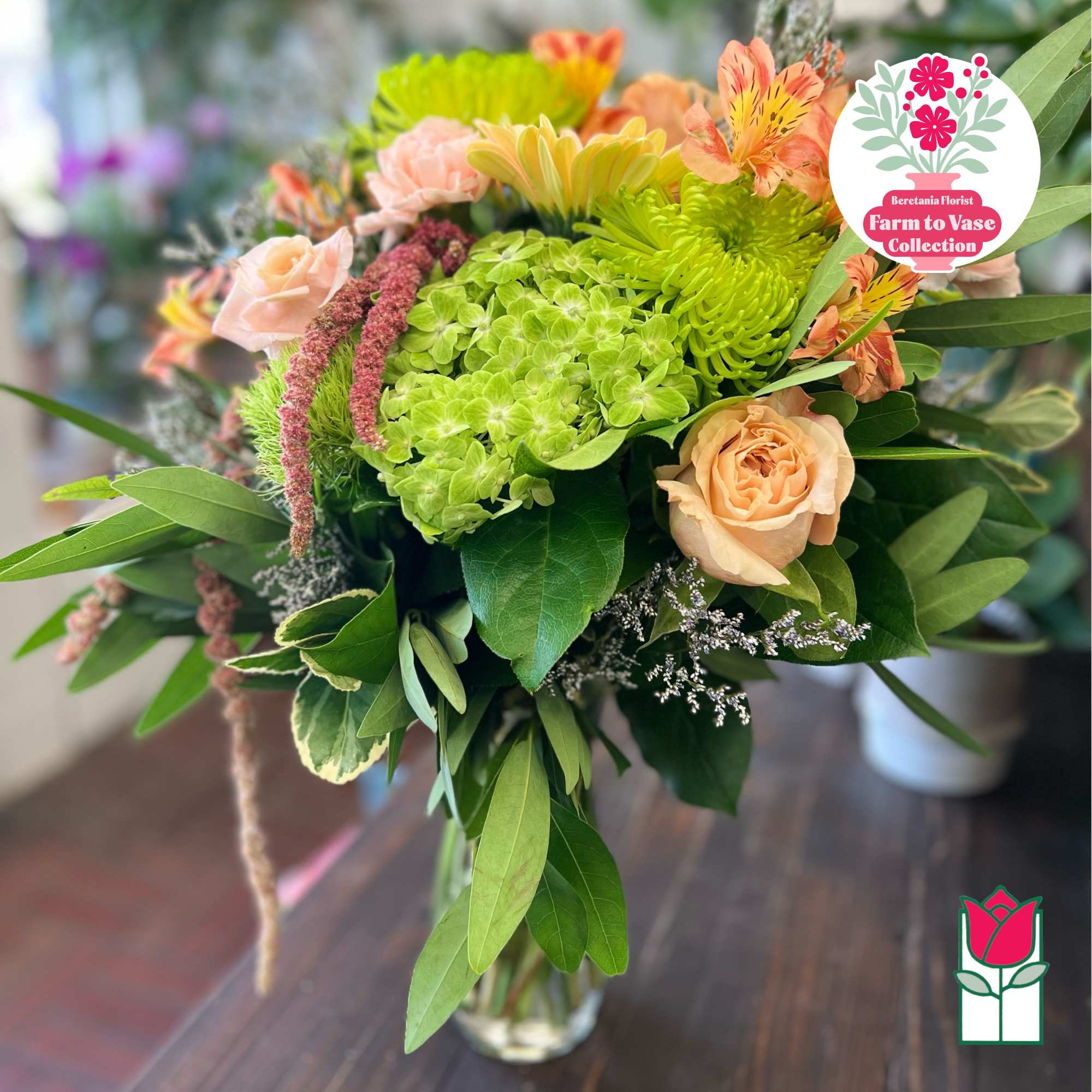 Mixed bouquet with peach roses, green hydrangea, and orange flowers in a glass vase