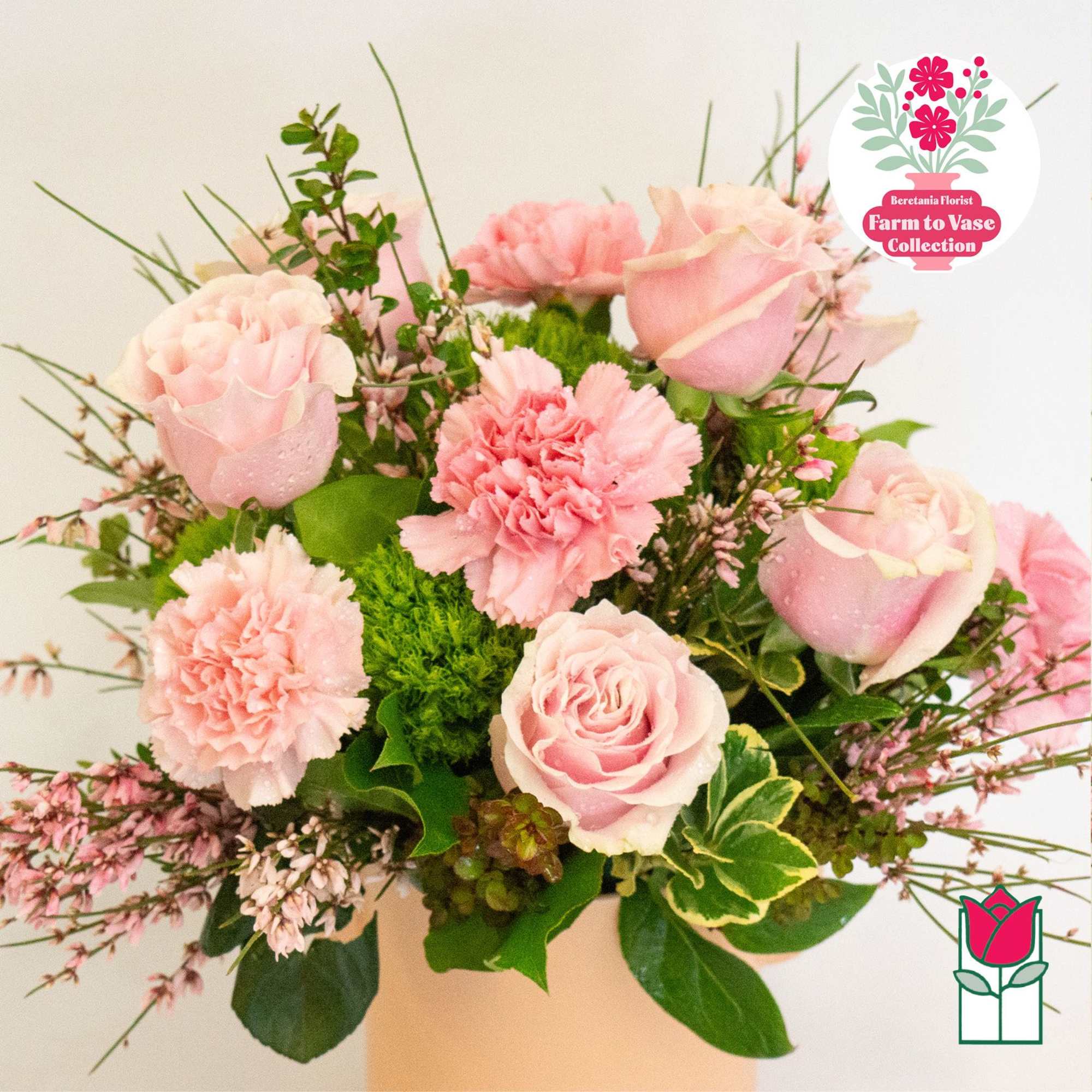 Pink roses and carnations arranged in a vase with greenery