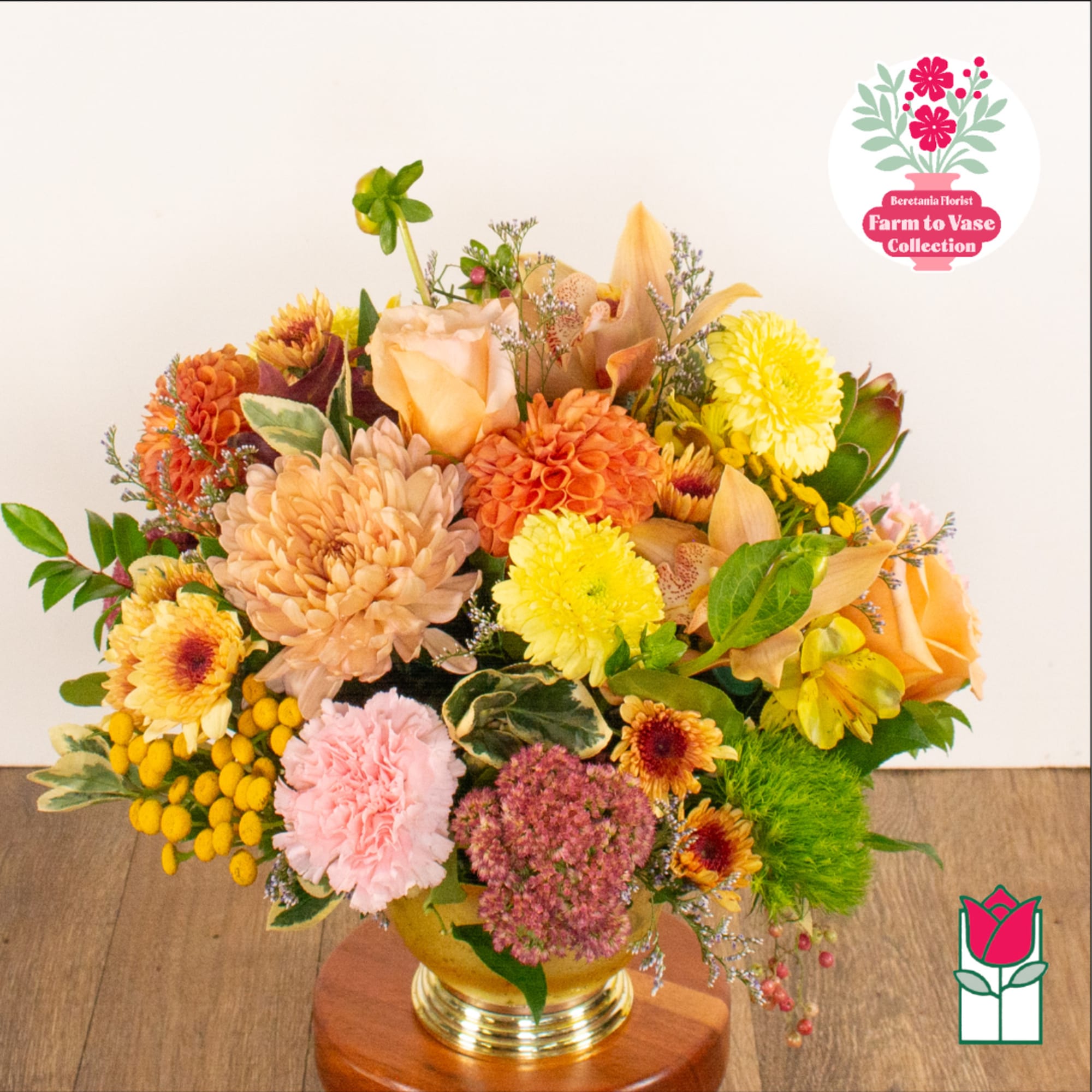 Mixed bouquet in a gold vase with peach, yellow, pink, and orange flowers
