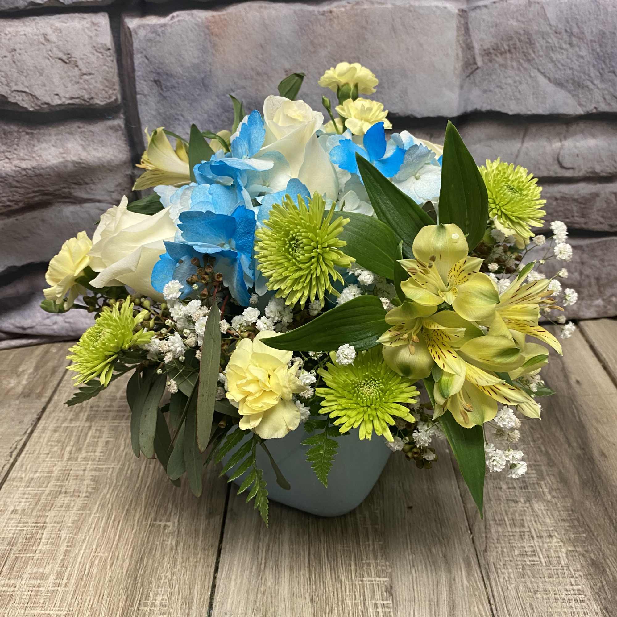 Mixed bouquet of blue, yellow, and white flowers in a vase