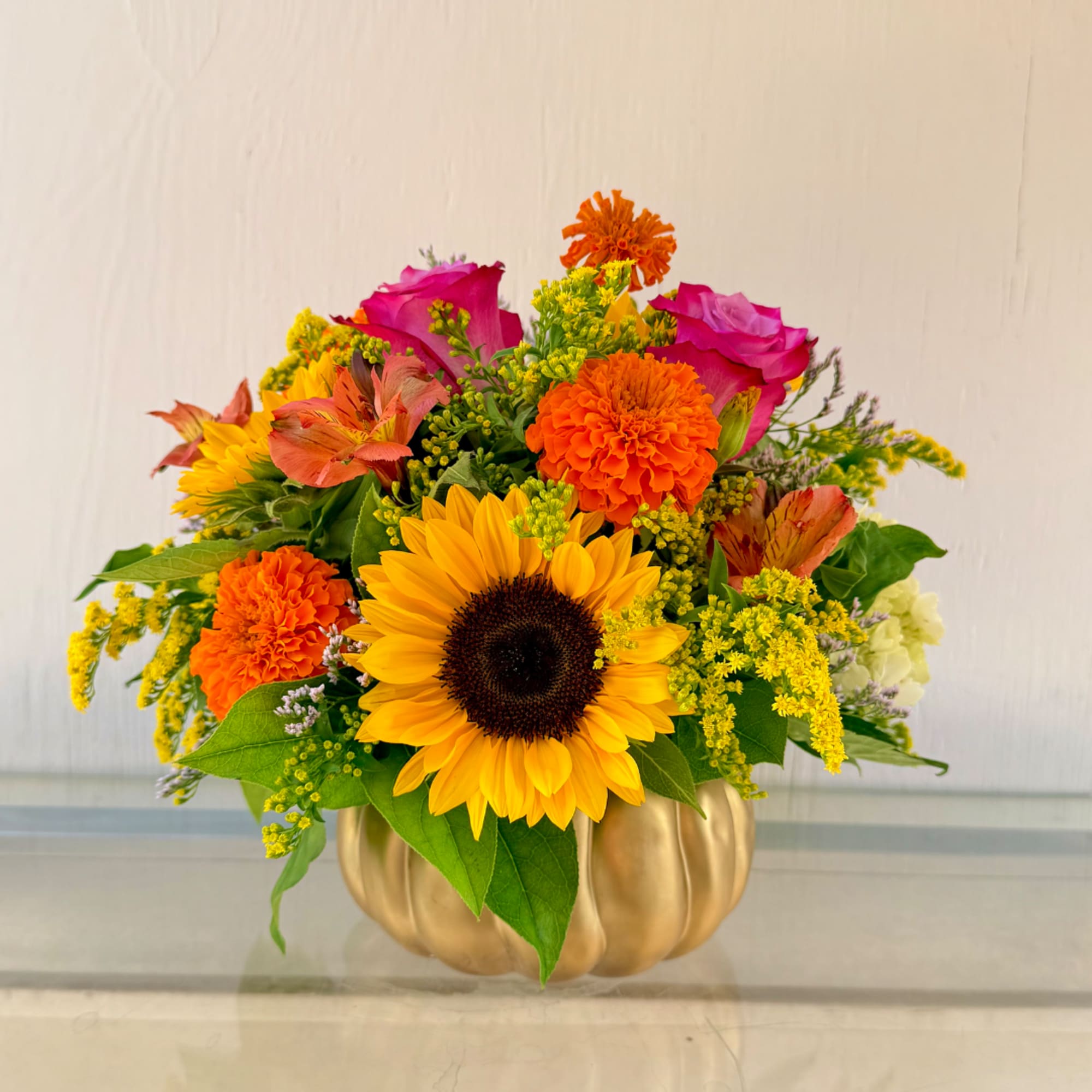 Bright mixed bouquet in a gold pumpkin-shaped vase