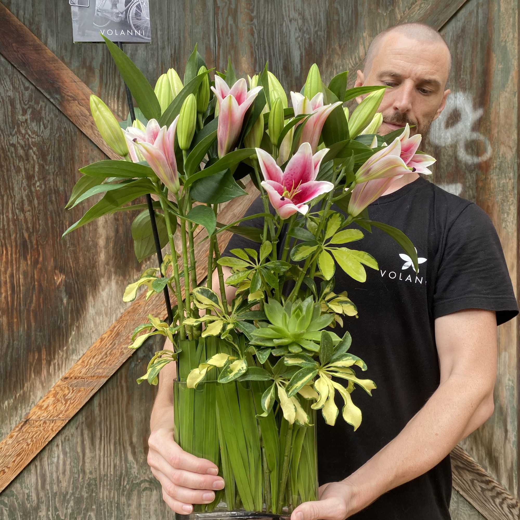 Tall arrangement of pink lilies in a clear rectangular vase