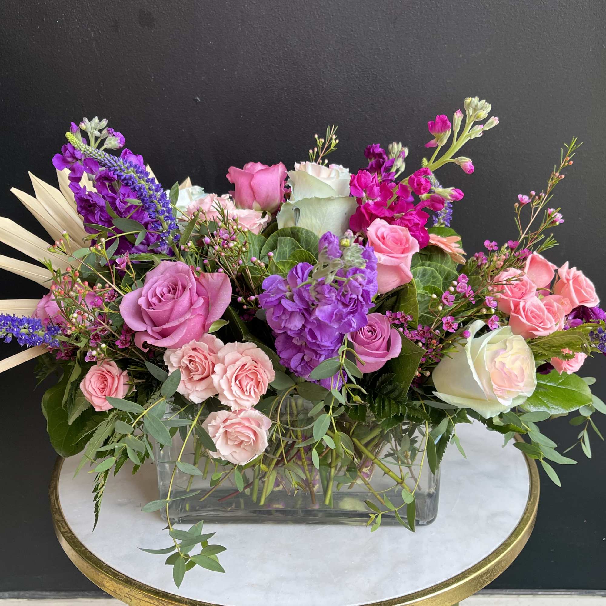 Pink and purple floral arrangement in a clear rectangular vase