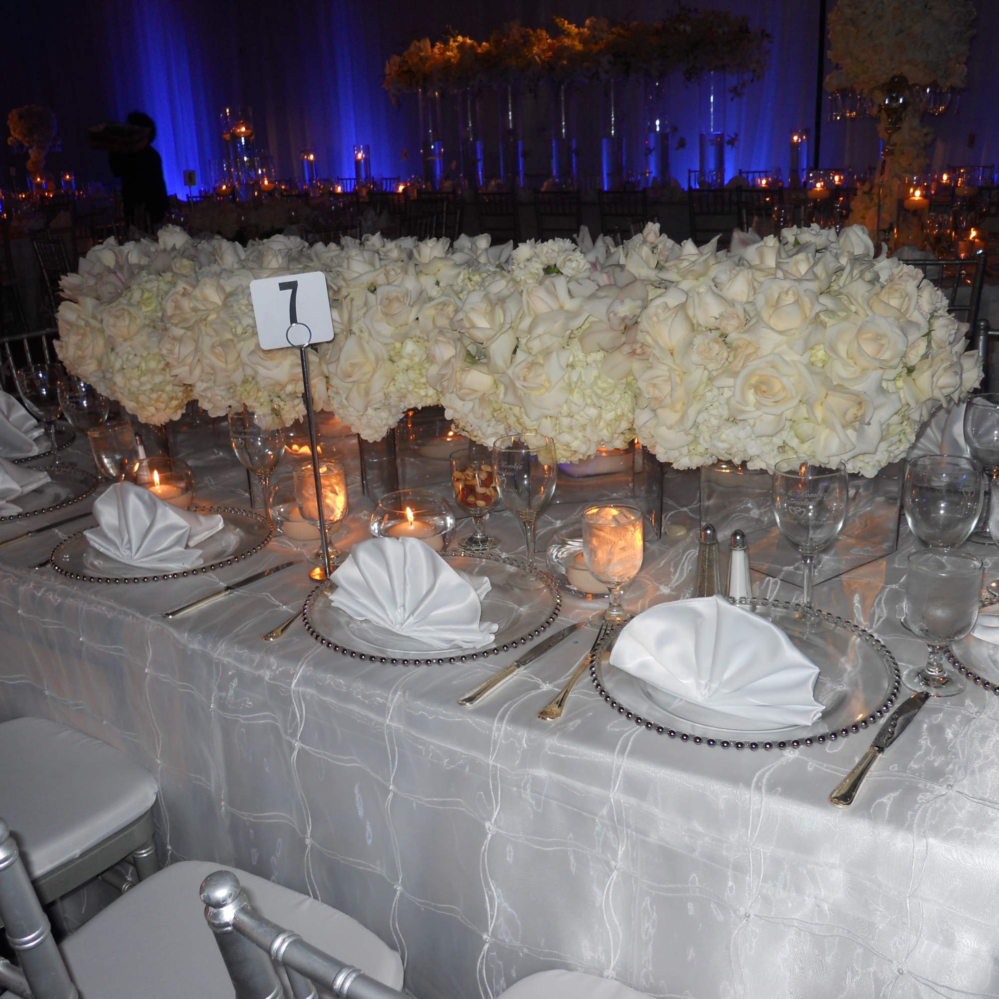 White rose centerpiece on a decorated banquet table with candles