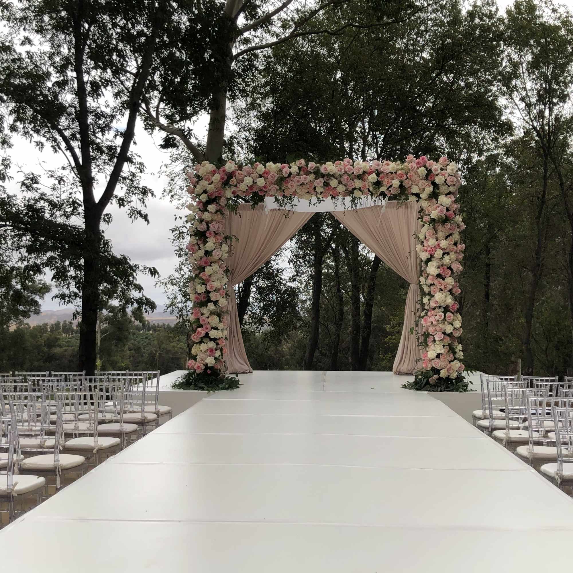 Outdoor wedding aisle with a floral arch and rows of chairs