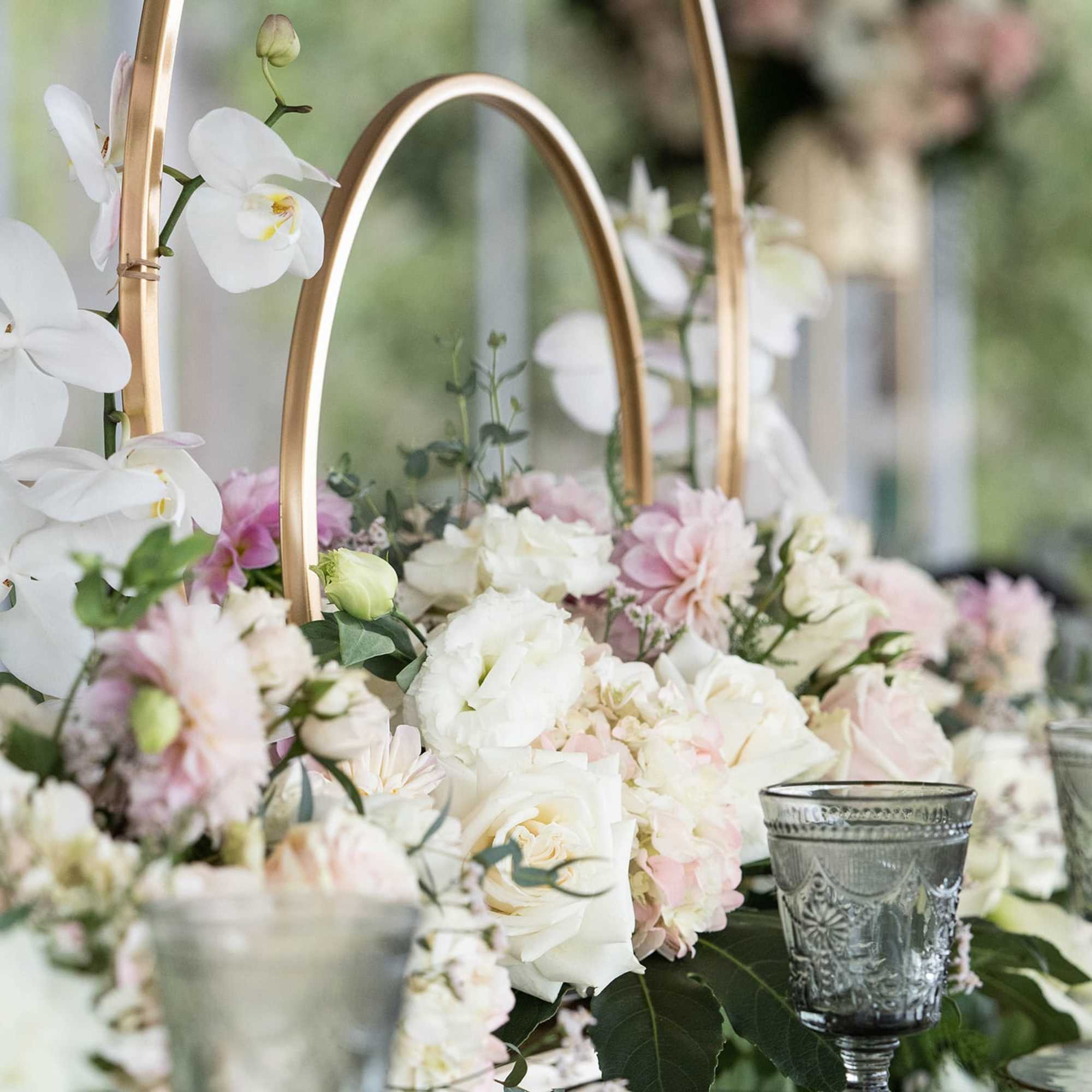 White orchids and blush flowers arranged around gold hoops