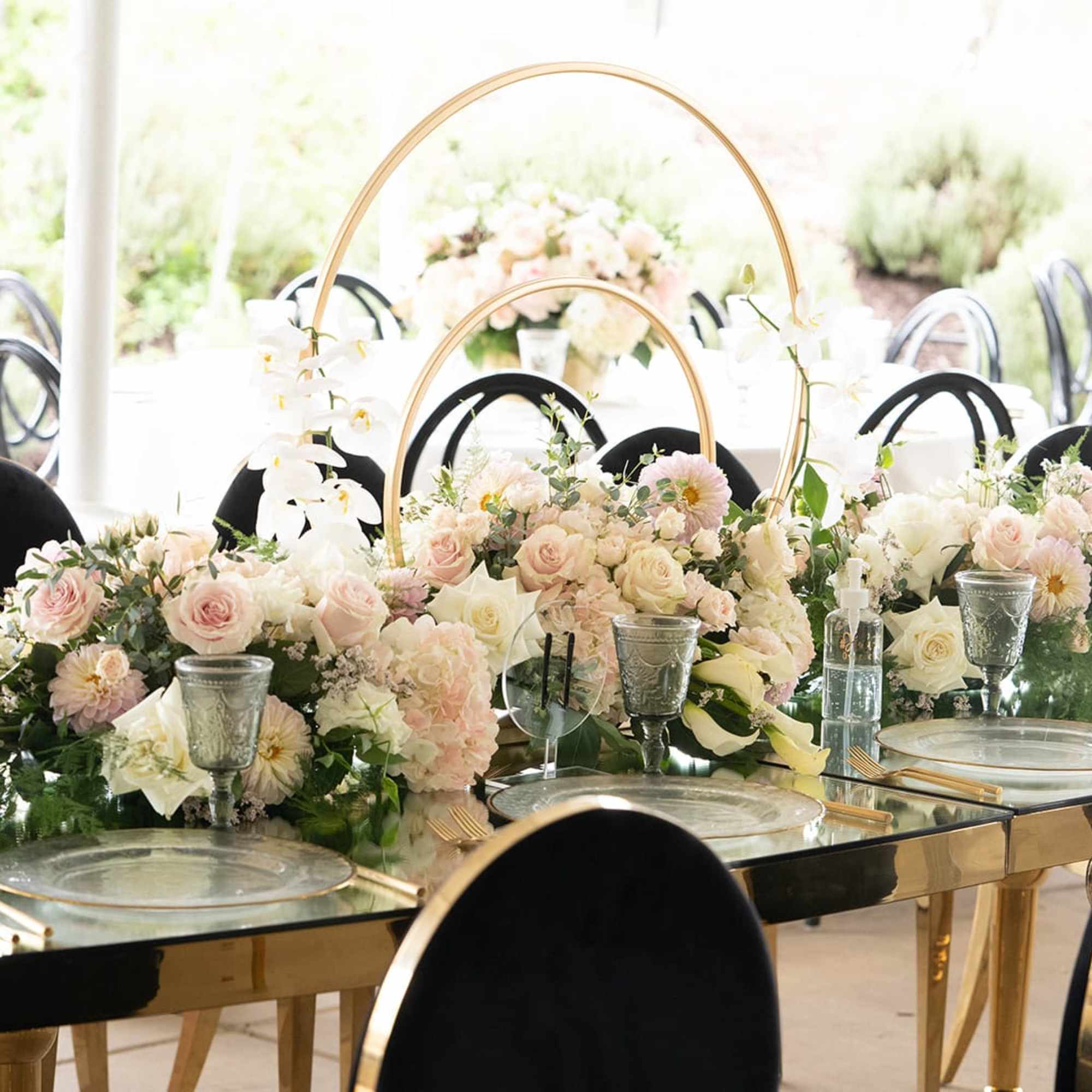 Pastel floral centerpieces on a mirrored banquet table with black chairs