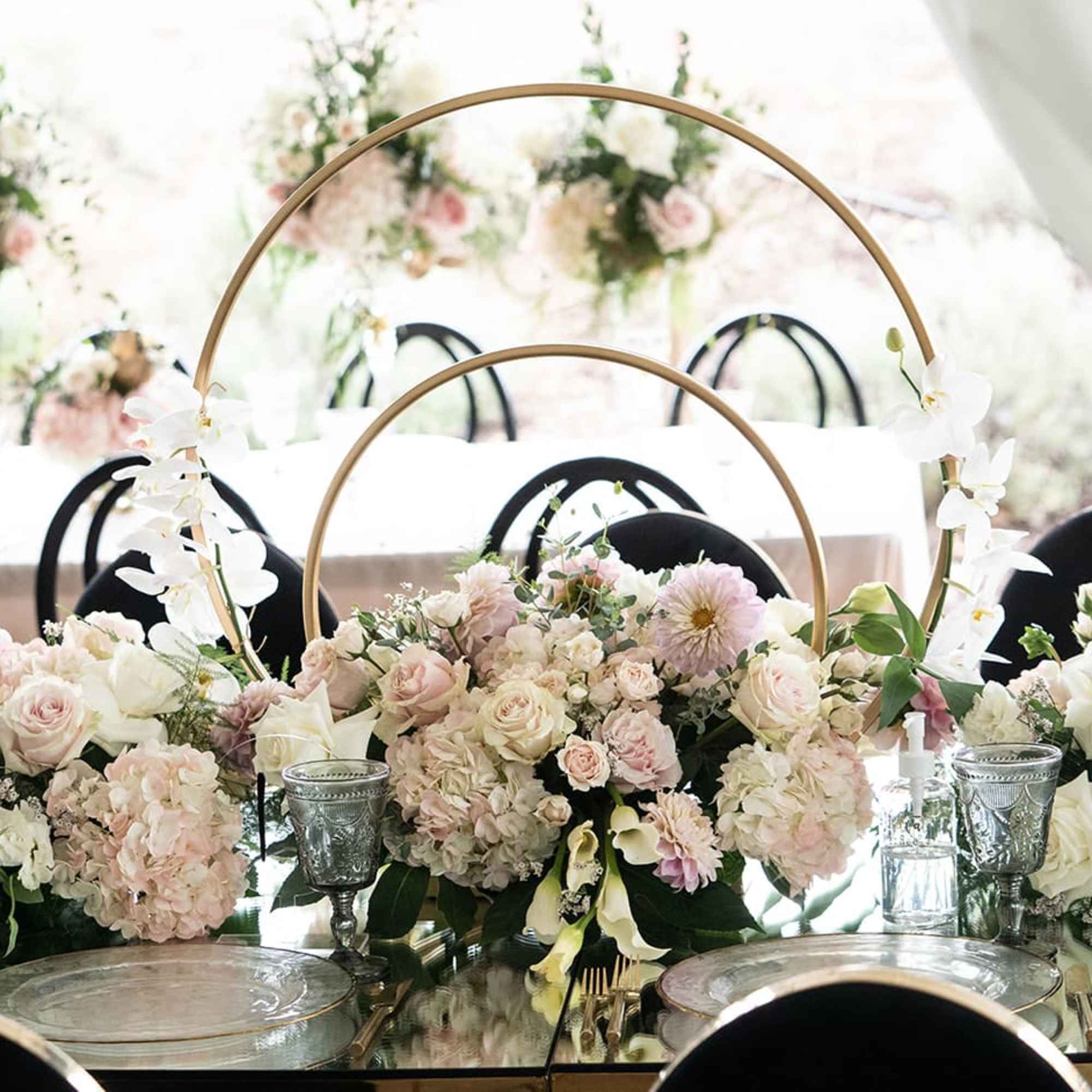 Pastel floral centerpiece with roses and dahlias around gold hoops