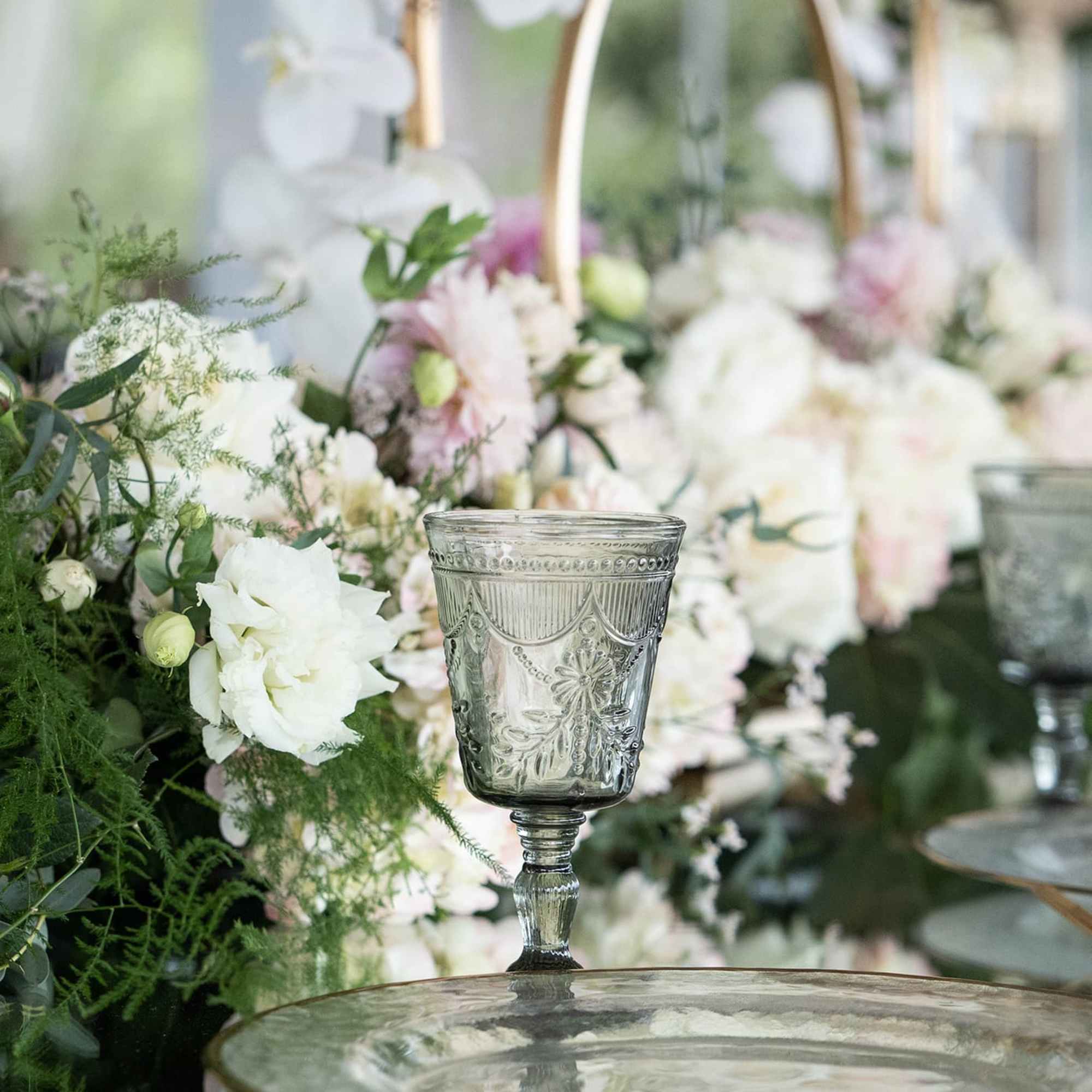 White and blush floral centerpieces in glass goblets on a table