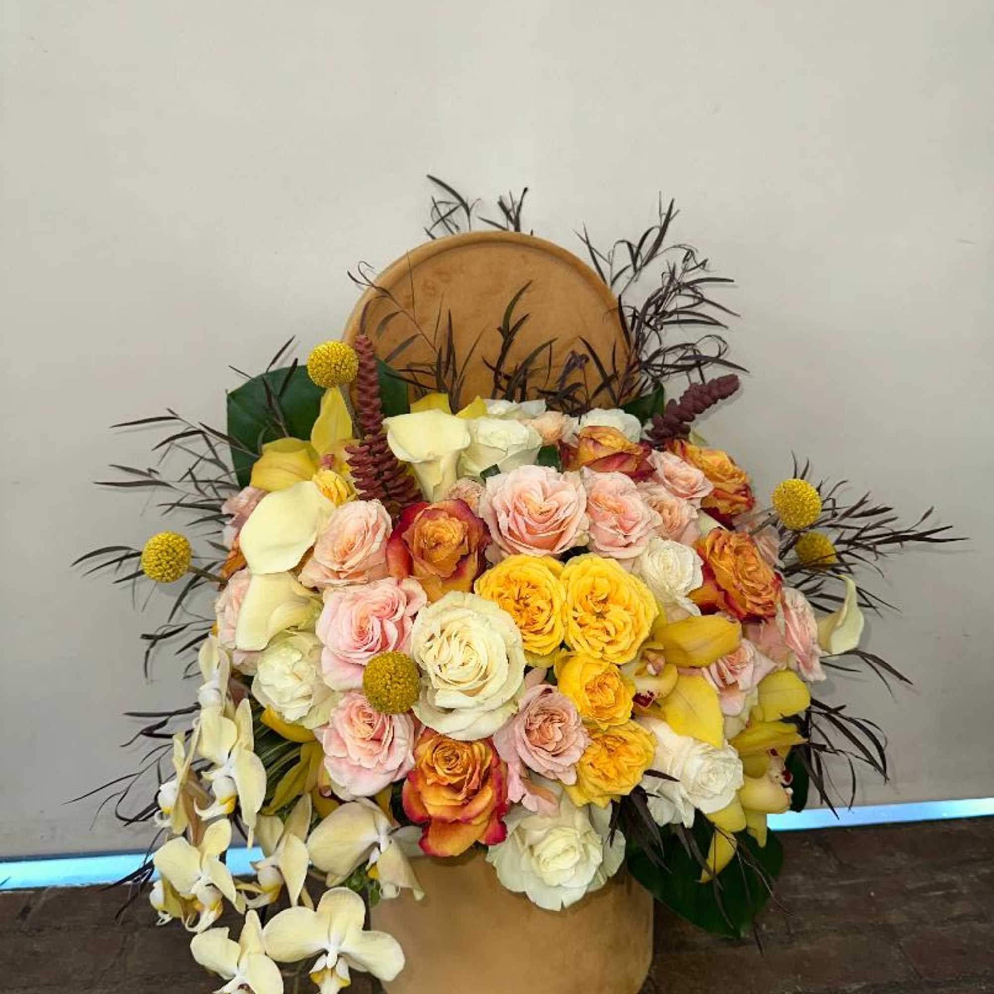 Large bouquet of roses and orchids in a tan hatbox
