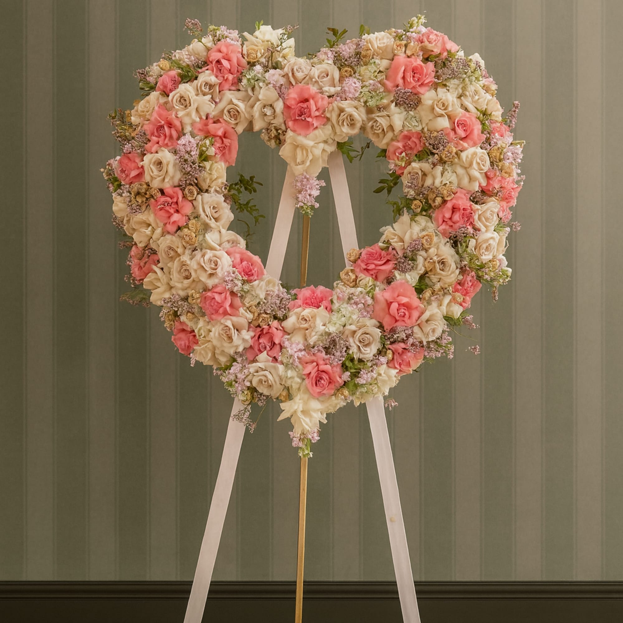 Heart-shaped floral wreath on an easel with pink and cream roses