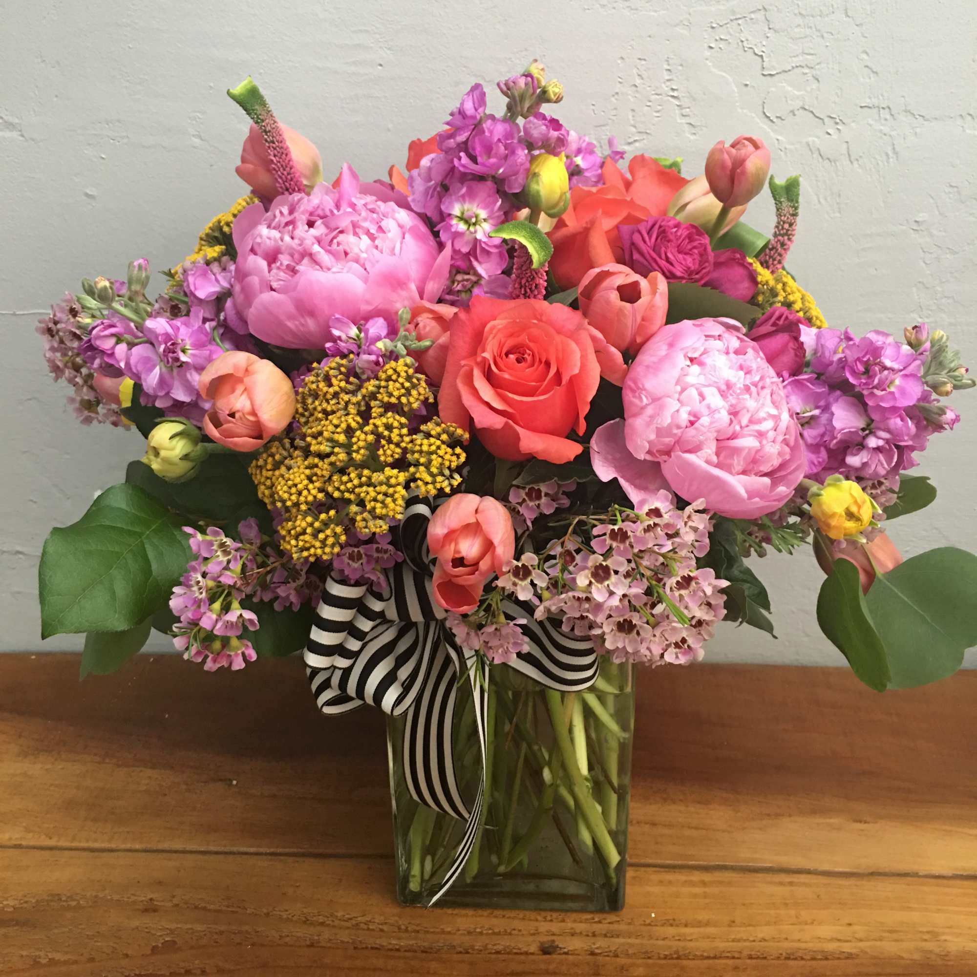 Colorful mixed bouquet in a glass vase with a striped ribbon