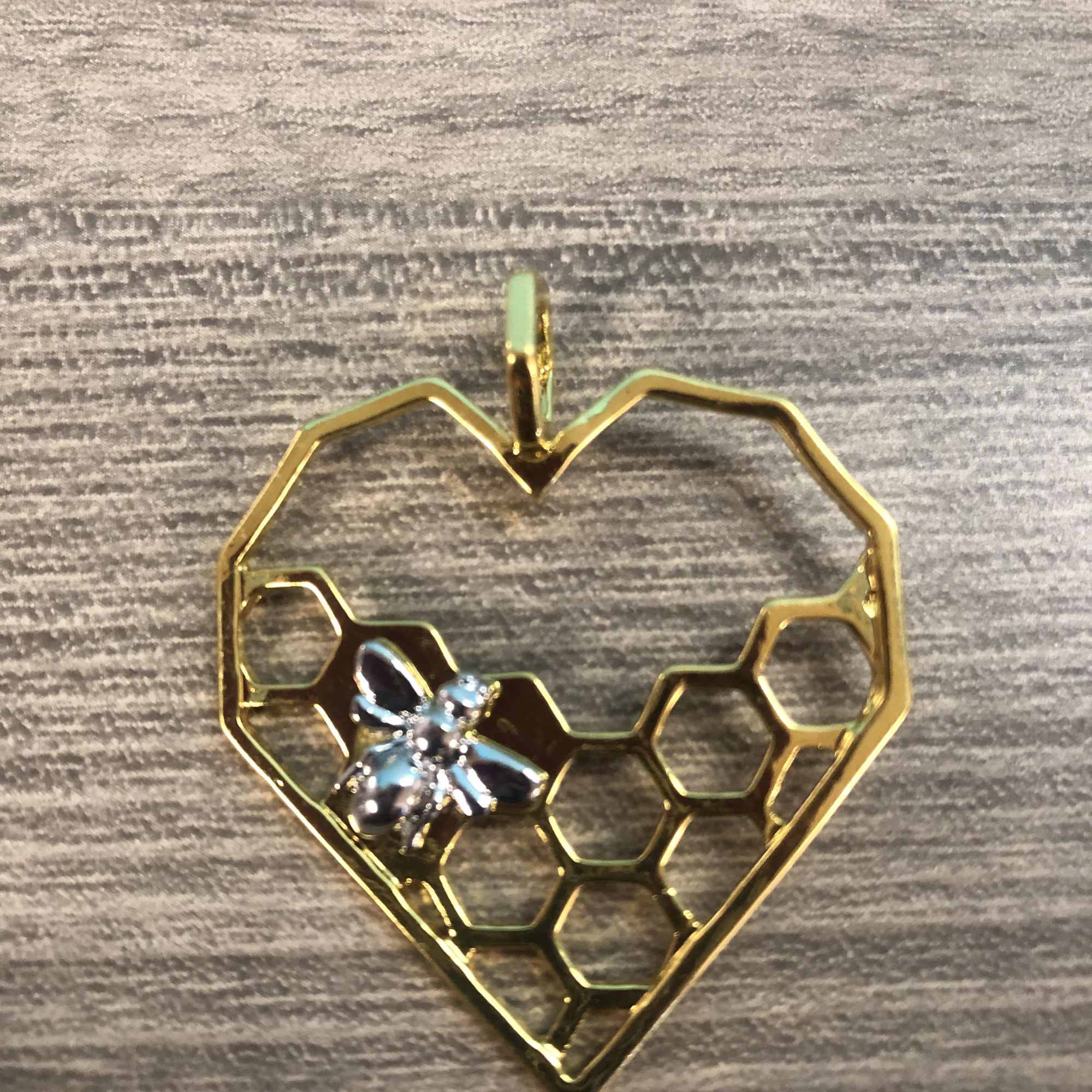 Gold heart-shaped pendant with a small bee charm