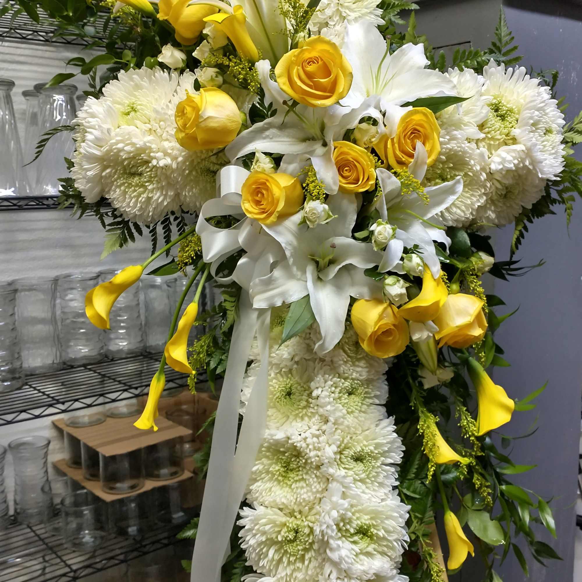 Large yellow and white floral standing spray with roses, lilies, and chrysanthemums