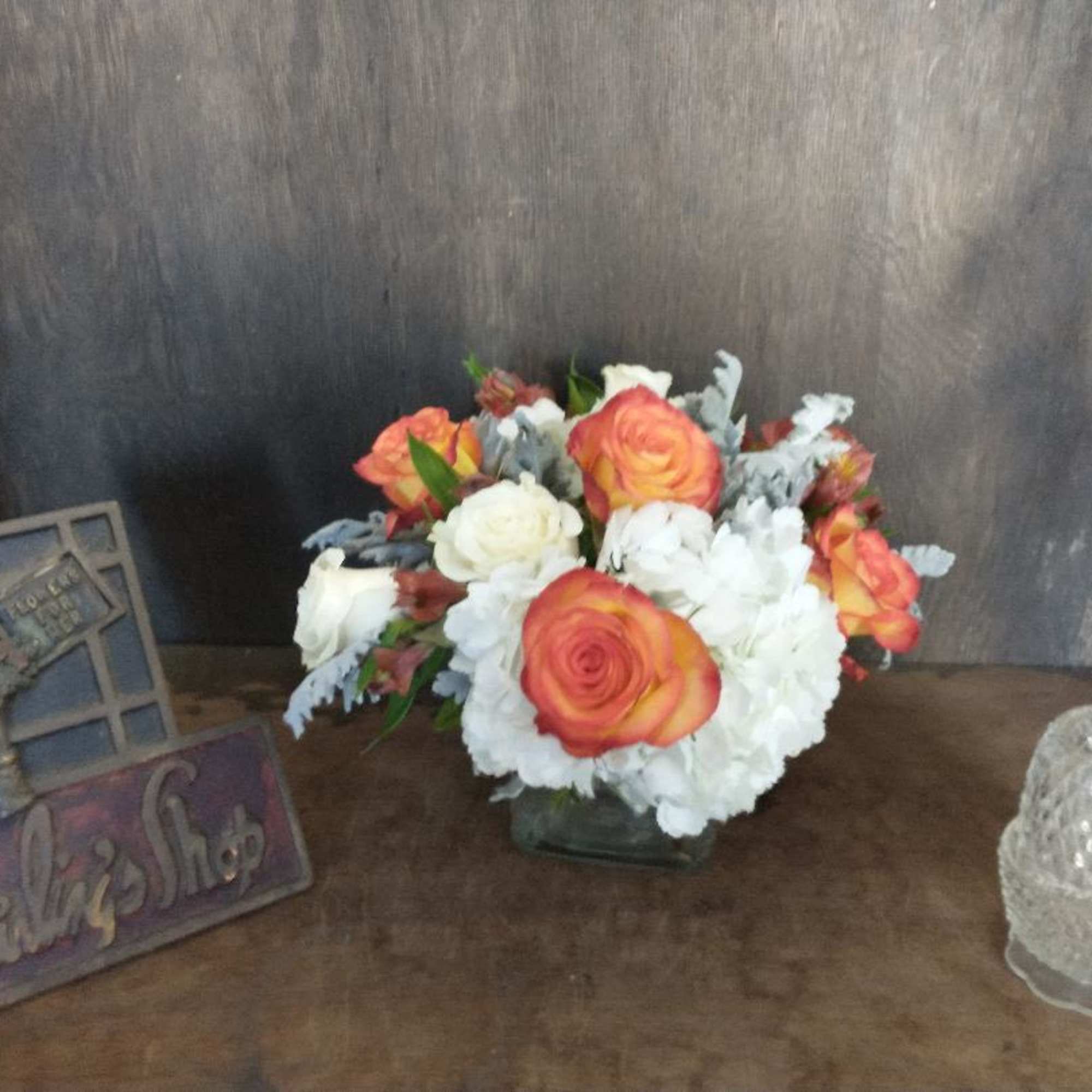 Orange and white roses arranged in a low glass vase