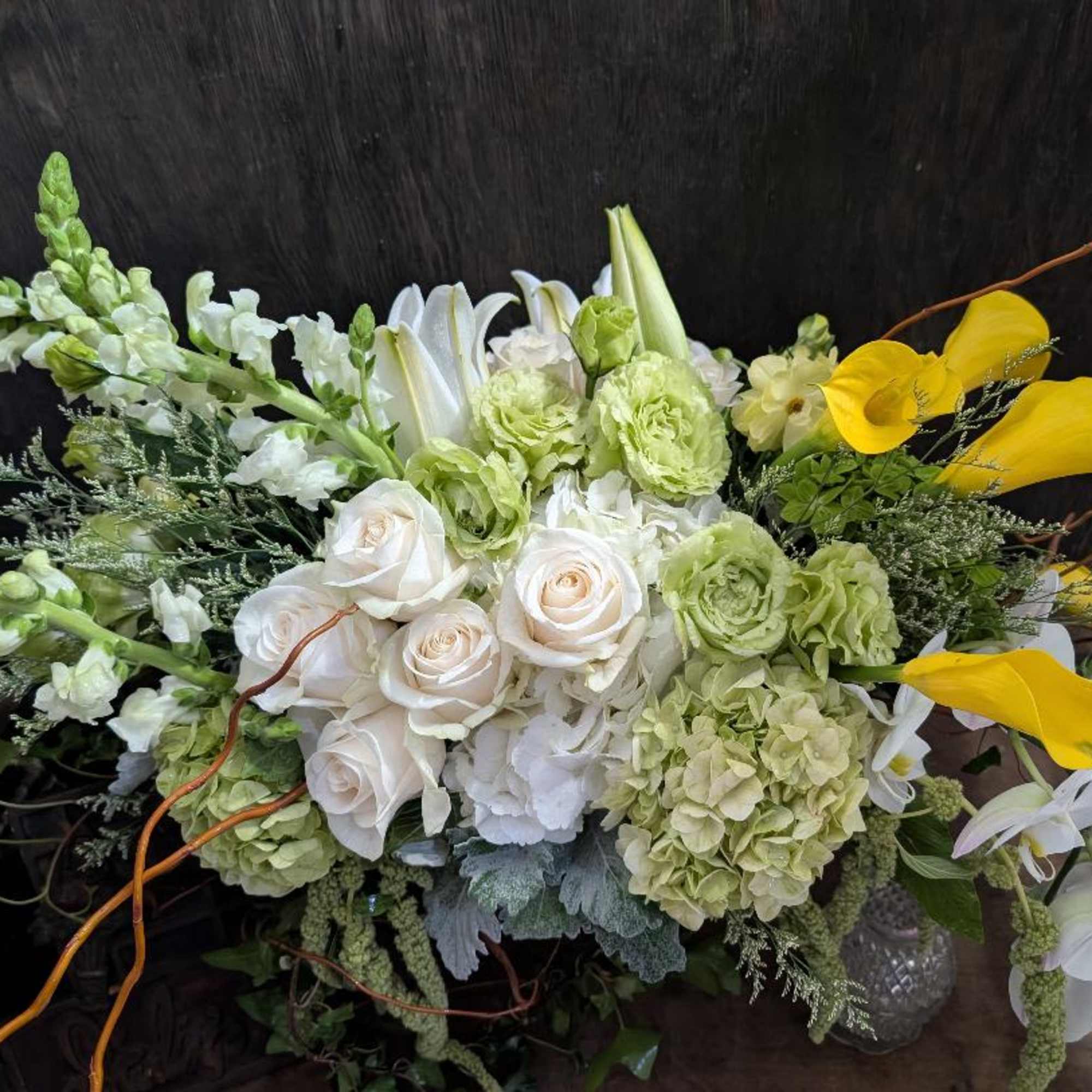 Bouquet of white roses, lilies, and green blooms with yellow calla lilies