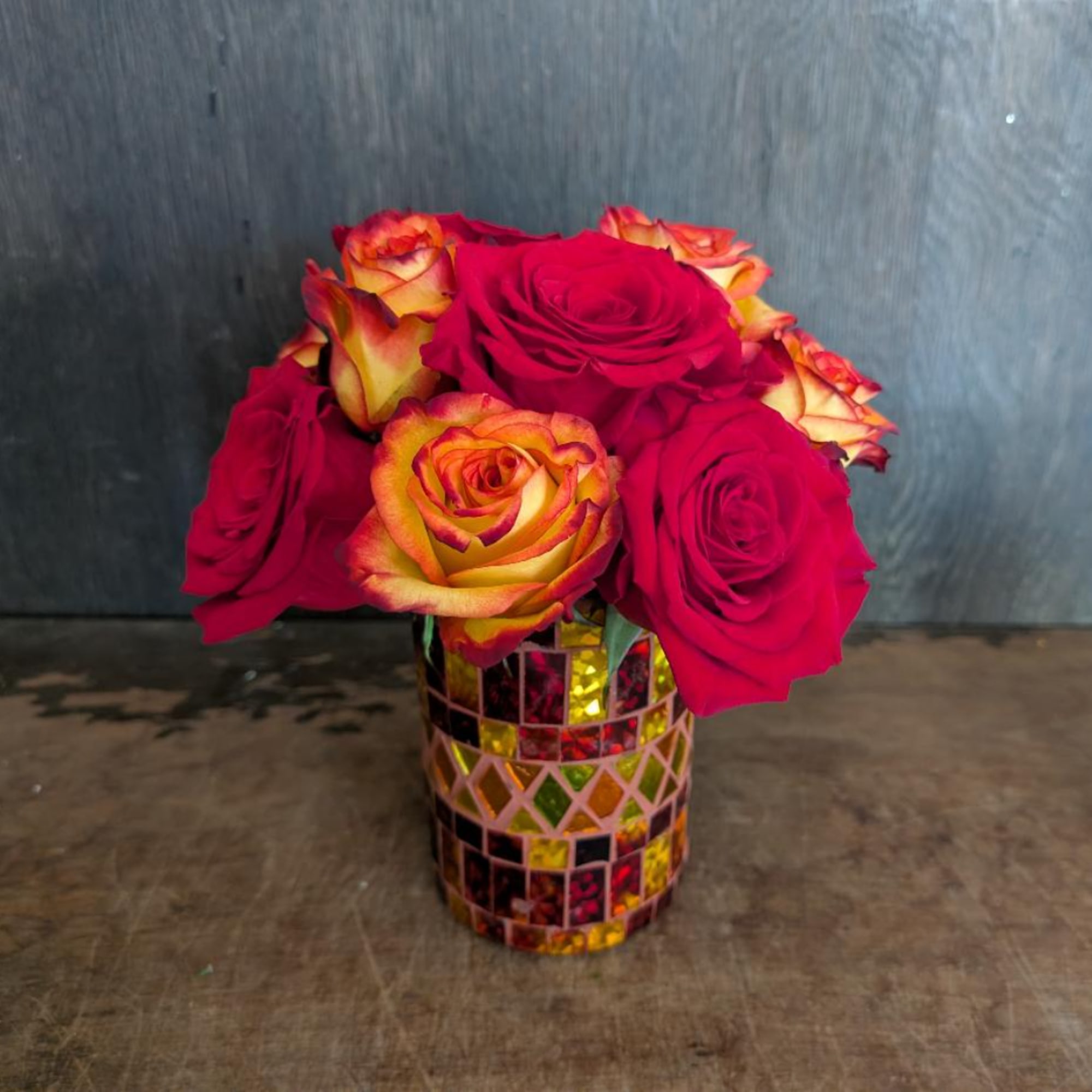 Red and yellow roses arranged in a mosaic vase